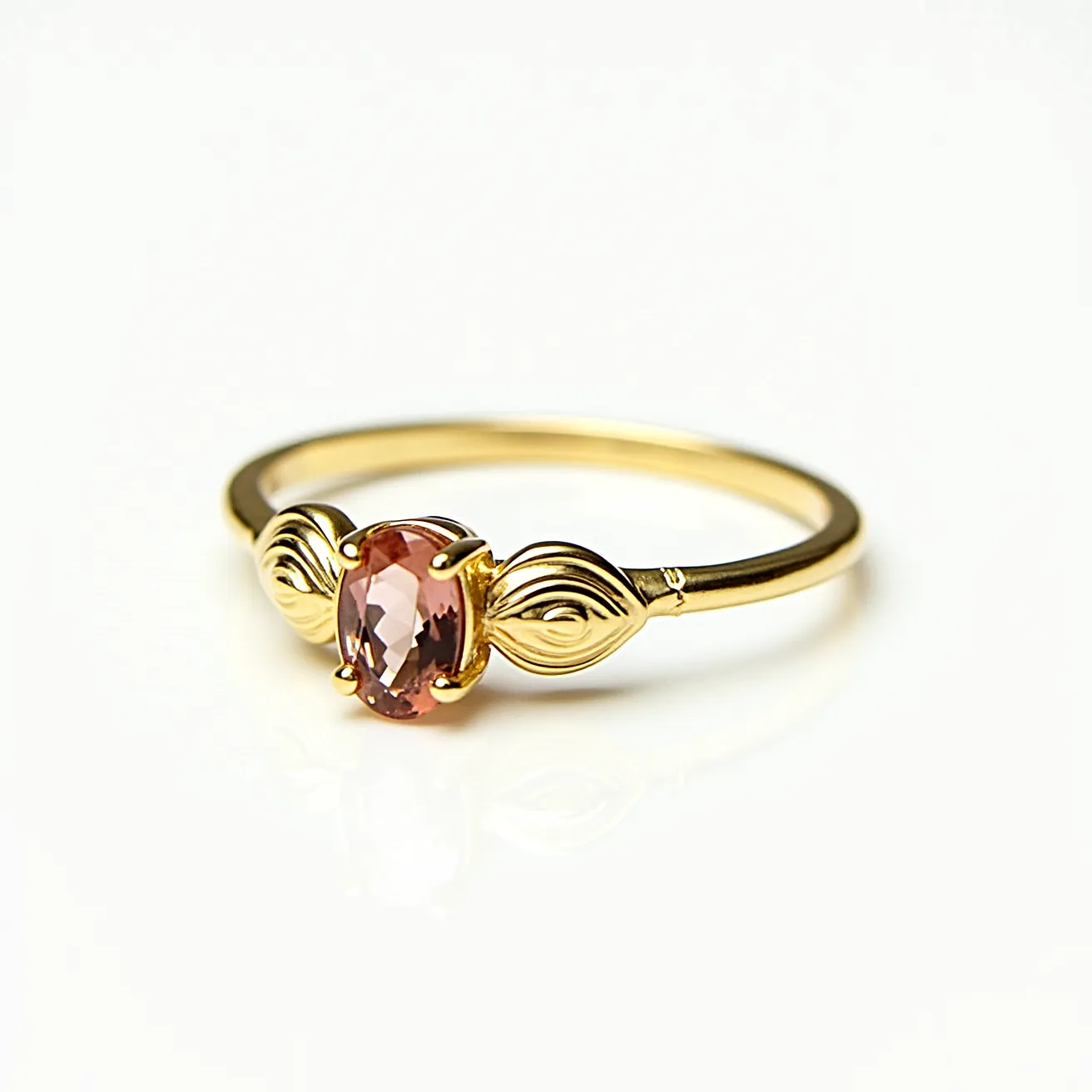 This rose ring features an elegant oval-cut pink gemstone set in a four-prong setting, enhancing its shimmering facets. The band appears to be crafted from gold, providing a warm complement to the blush hue of the stone. Flanking the gemstone, intricate metallic leaf-like motifs add a touch of artistic detail to the design. The simplicity of the band allows the central stone and motifs to take focus, showcasing a blend of classic and nature-inspired aesthetics.