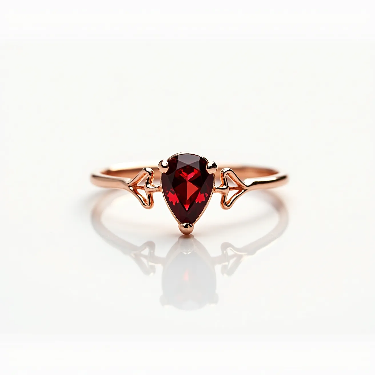 This ruby ring features a polished rose gold band that gracefully holds a central ruby gemstone. The ruby is cut into a pear shape, showcasing its deep red hue. It is securely held in a prong setting that enhances its elegance and brilliance. Unique details on the band, providing an artistic flair, draw attention to the gem, making it a standout piece. The combination of the warm rose gold and vibrant ruby offers a sophisticated and timeless look.