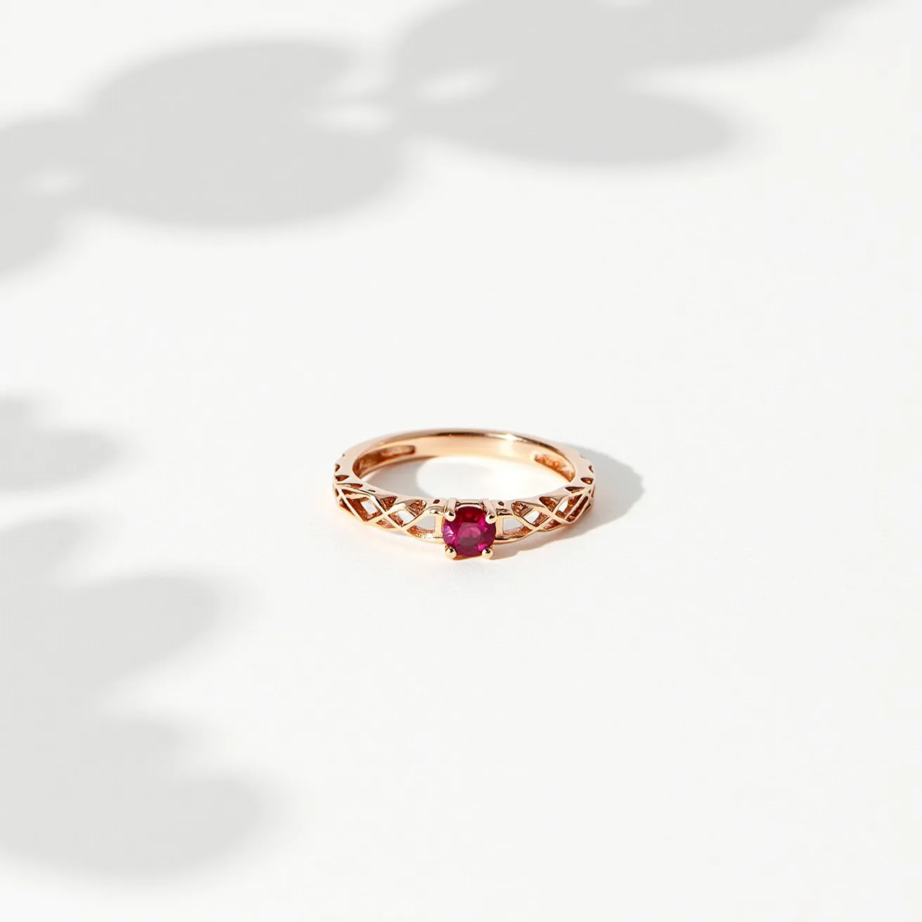 This ruby ring features a single round-cut ruby set in a delicate, intricately designed gold band. The vivid red gemstone is securely held in place by a prong setting, allowing maximum light exposure to enhance its natural brilliance. The band itself showcases an elegant lattice pattern, which adds a touch of sophistication and texture. The warm hue of the gold complements the rich red of the ruby, creating a harmonious and luxurious design without any visible clasps or attachments.