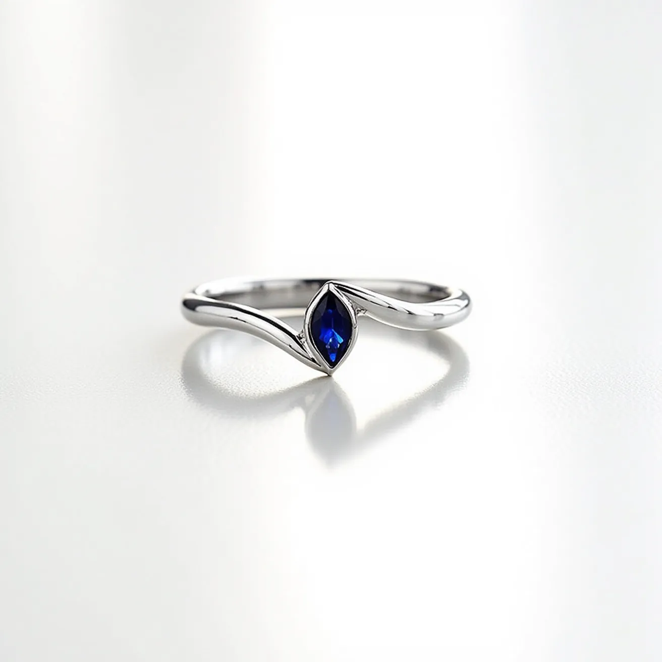 This sapphire ring features a marquise-cut blue sapphire set securely within a sleek, polished band, likely made of white gold or platinum. The elegant design showcases the sapphire as the central focal point, with a bezel setting that enhances its shape and protects the stone. The band has a graceful, fluid form that complements the marquise cut, adding a touch of sophistication and modernity to the piece.