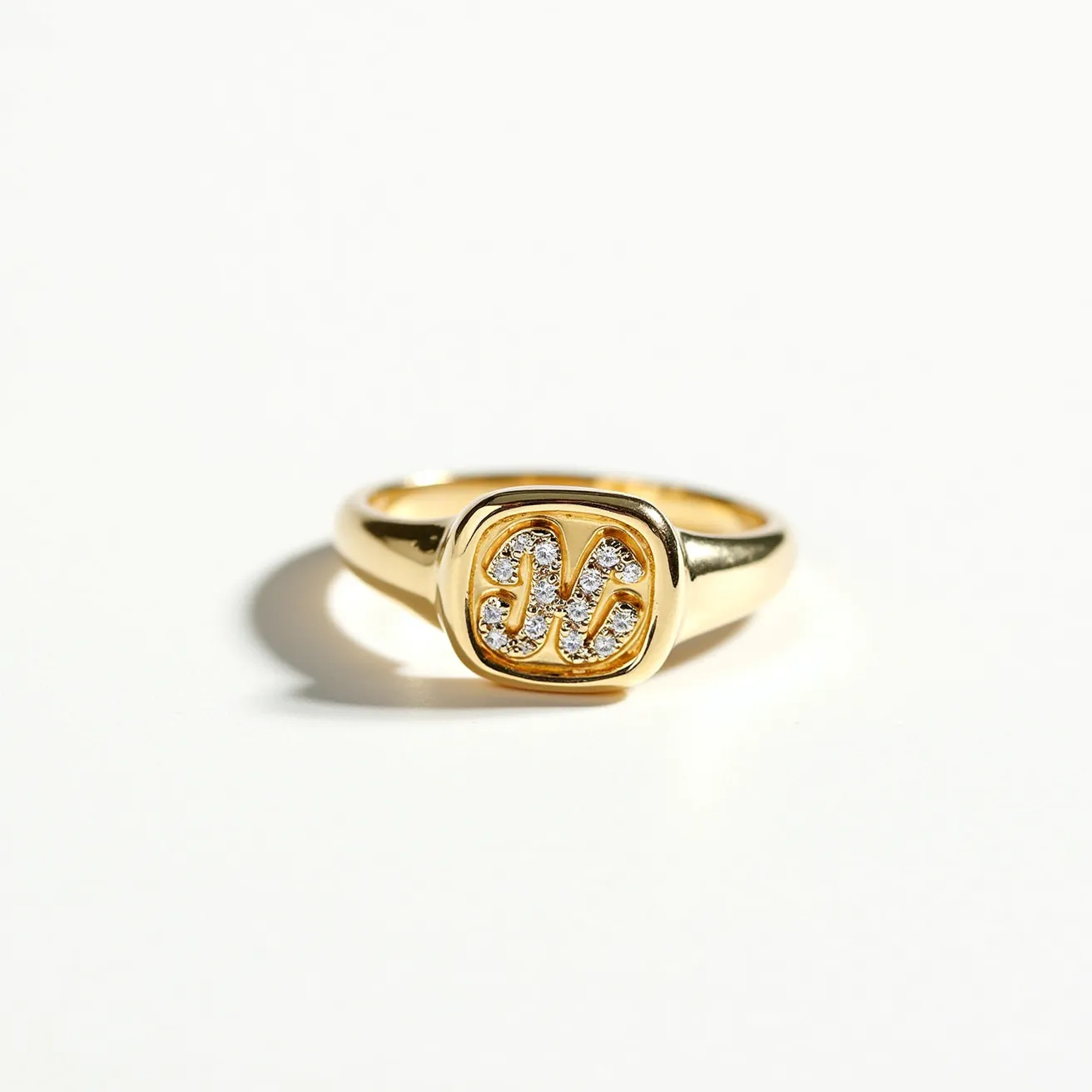 This signet ring is crafted from a polished yellow gold material, featuring an elegantly designed emblem on the top surface. The emblem is adorned with small, intricately set diamonds that form decorative initials in a pavé setting, adding a touch of sparkle and sophistication to the overall design. The ring's band tapers smoothly, ensuring a comfortable fit, and the top portion is seamlessly integrated with the band, showcasing the craftsmanship involved in its creation. The overall appearance exudes luxury and a personalized touch, typical of traditional signet rings.