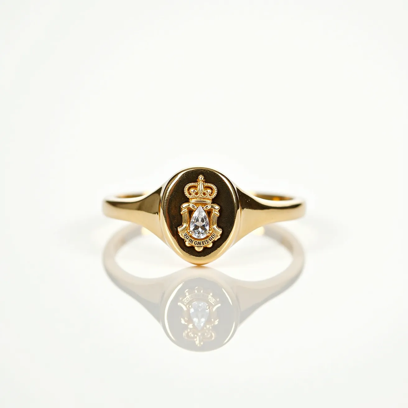 This signet ring features a sleek gold band with a polished oval face. At the center of the oval, there is a pear-shaped clear gemstone delicately set in a bezel setting, offering a touch of sophistication and elegance. Above the gemstone, an intricate crown design adds a regal flair, while below it, a banner with engraved text provides an additional decorative element. The craftsmanship of the ring highlights both luxury and attention to detail.