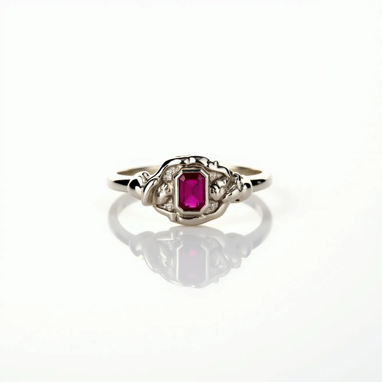 This signet ring features a vibrant, rectangular-cut ruby set in a bezel style. The metal appears to be polished silver, and the band is intricately designed with ornate detailing around the central gemstone. The ruby's deep red hue provides a striking contrast to the cool tone of the silver, enhancing its visual appeal. The absence of any visible clasp indicates that the ring is a seamless piece, designed for easy wear and removal. The craftsmanship reflects a balance of elegance and durability, typical of a well-made signet ring.