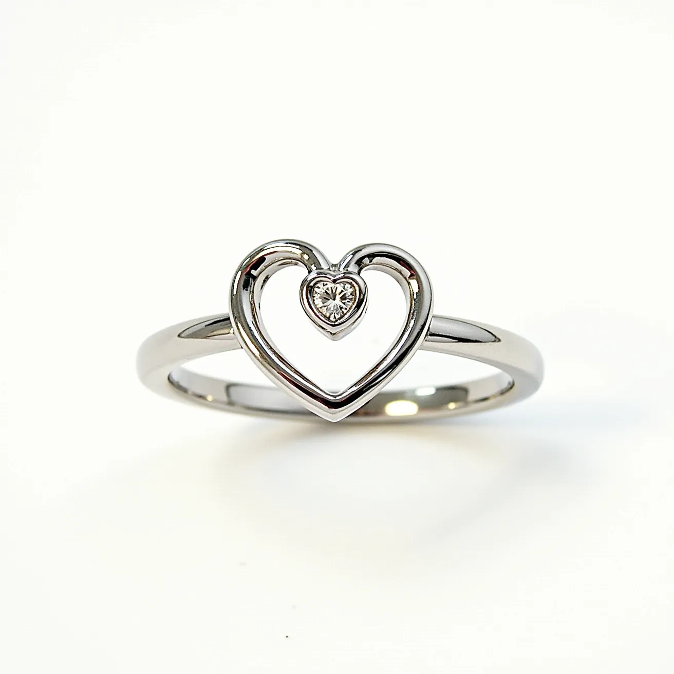 This silver heart ring features a sleek and polished band crafted from high-quality silver, which provides a refined and elegant appearance. At the center, the ring showcases a beautifully designed open heart motif, housing a central gemstone that appears to be a heart-cut diamond. The gemstone is securely set, enhancing its brilliance and sparkle. The combination of the silver and the gem creates a timeless and romantic aesthetic, making this ring both a charming and sophisticated piece of jewelry.