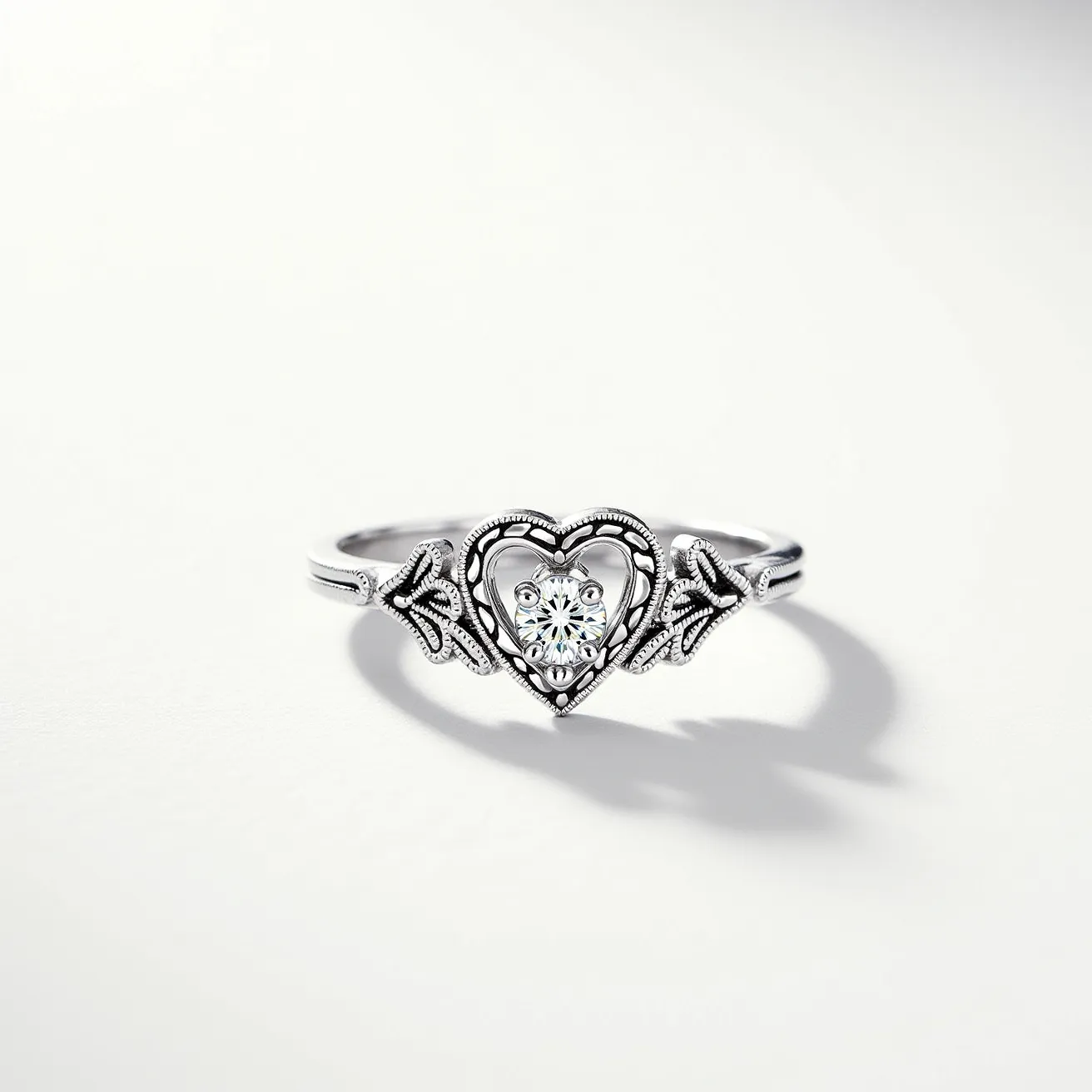 This silver heart ring features a delicately crafted heart design as its centerpiece, adorned with a sparkling round-cut gemstone set in a prong setting. The heart shape is elegantly framed by intricate silver detailing that enhances its intricate appearance. The band is decorated with additional ornamental elements, adding to its overall charm and sophistication. The use of silver as the primary material gives the ring a timeless and elegant look, making it a versatile accessory suitable for various occasions.