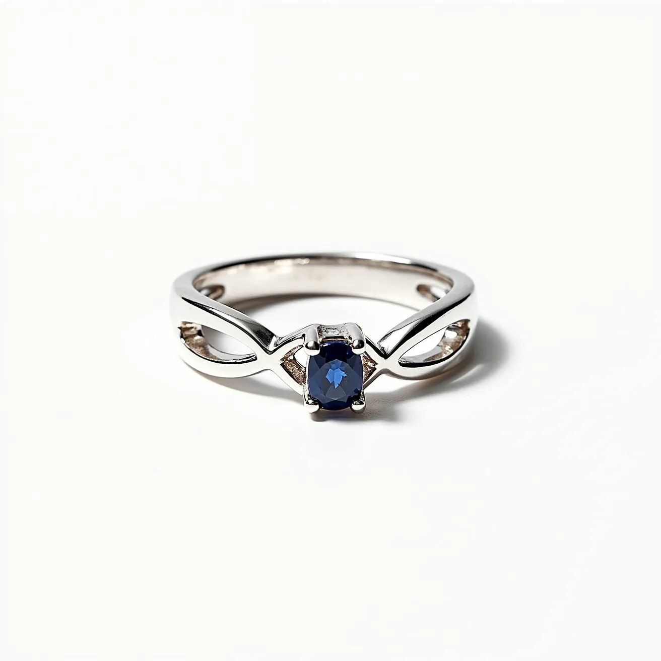 This silver promise ring features a sleek, intertwined band design crafted from polished silver, lending it a modern elegance. At its center is a single, captivating gemstone, likely an oval-cut sapphire, held securely in place by a four-prong setting that enhances its deep blue hue. The design cleverly integrates the open band style with the setting, creating a seamless look that symbolizes unity and commitment.