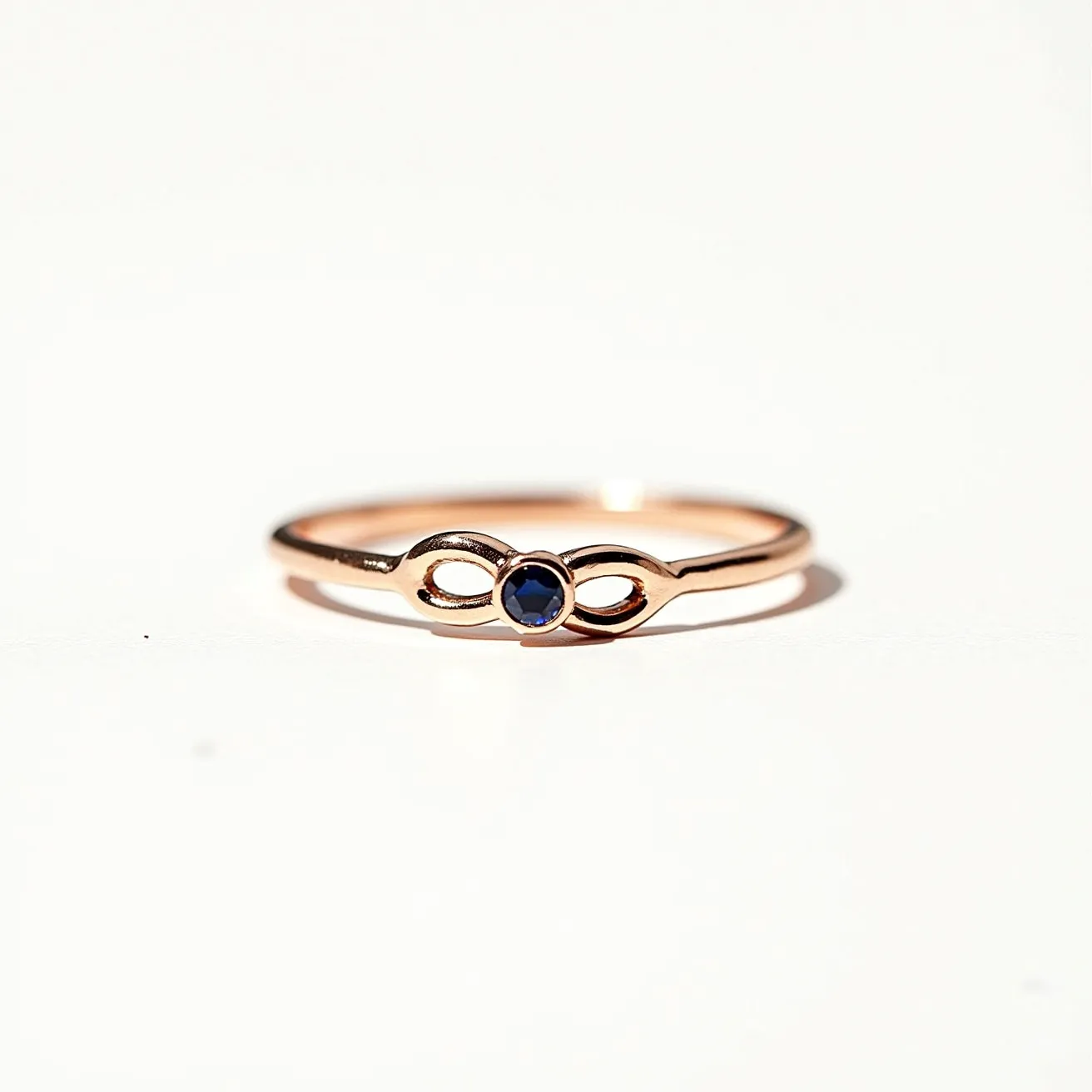 This silver promise ring features a delicate and sleek design, crafted from silver with a lustrous finish. Its centerpiece is a round-cut stone, likely a sapphire, set in a bezel setting that securely holds the gem while allowing it to shine. The band incorporates a charming infinity symbol, symbolizing eternal love and commitment. The overall design is minimalistic and elegant, making it an ideal choice for symbolizing a heartfelt promise.