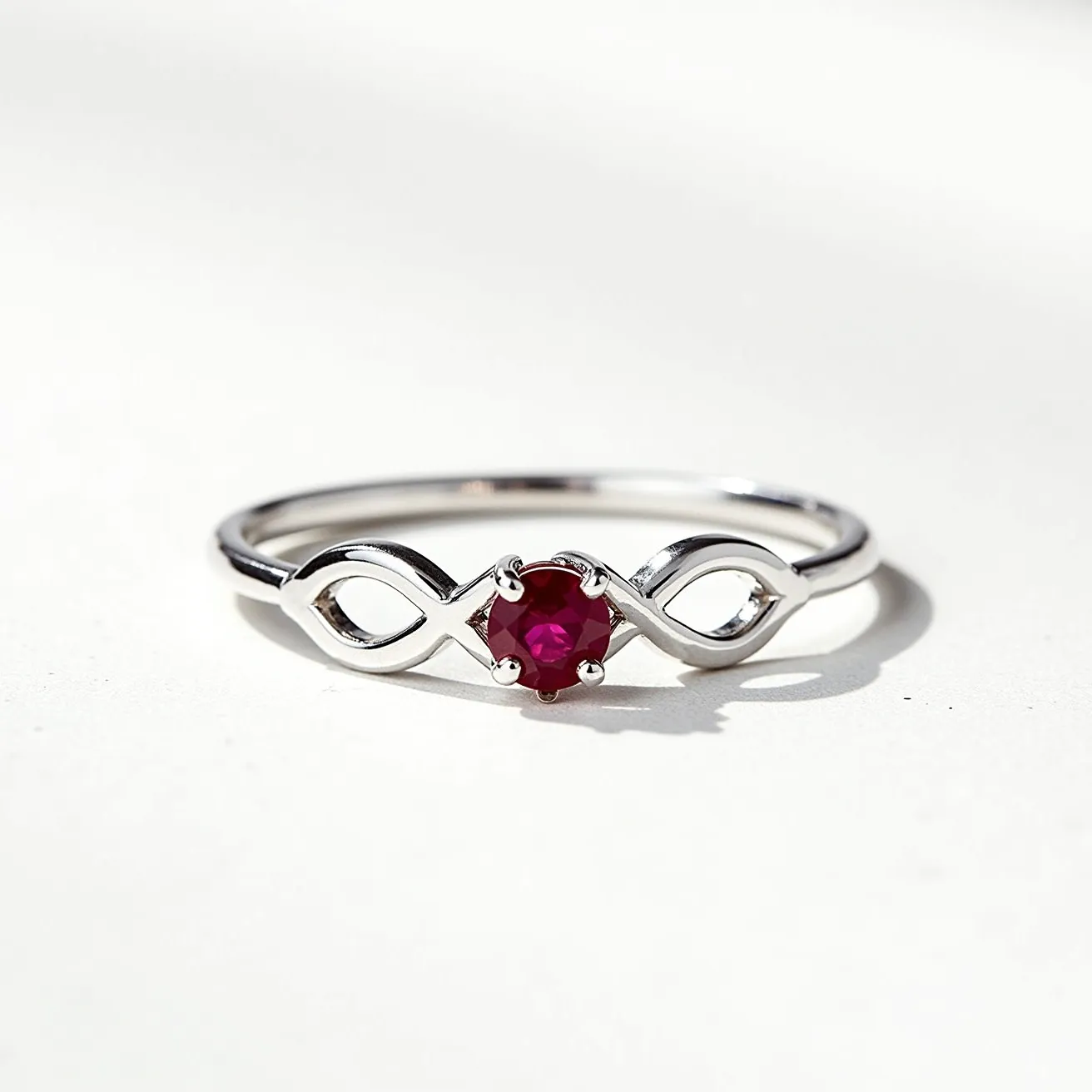 This silver promise ring features an elegant design crafted from silver, showcasing an infinity symbol on its band. At the center of the ring is a single, round-cut red gemstone, likely a ruby, held securely in place by a four-prong setting. The infinity motif on either side of the gemstone adds a touch of elegance and symbolizes eternal love and commitment. The ring's minimalist yet meaningful design makes it an ideal token of promise and affection.