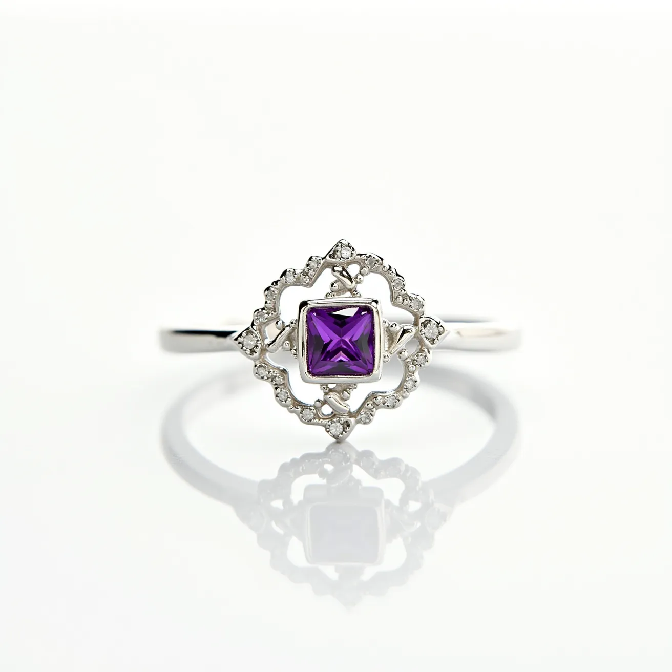 This silver ring features an intricate design with a prominent central gemstone. The gemstone is a square-cut purple stone, held securely in place by a bezel setting. Surrounding the central gem is an ornate frame embellished with small clear stones, likely diamonds or cubic zirconia, providing a delicate and refined contrast. The band of the ring is smooth and slender, complementing the detailed focal point without any additional clasps or attachments.