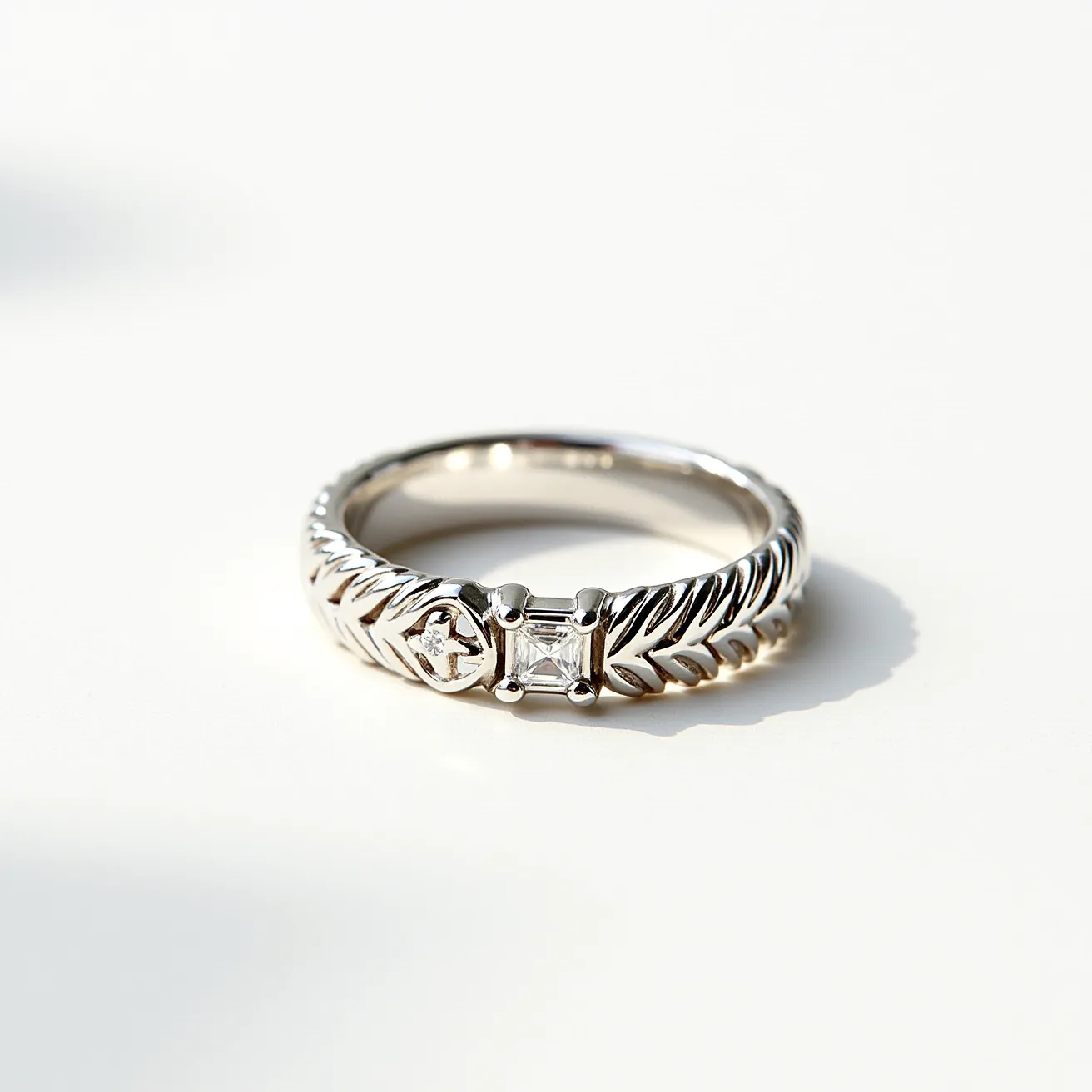 This silver wedding ring features a distinctive band with an intricate, woven-like pattern that gives it a textured and elegant appearance. The ring is adorned with two prominent stones; one is a round cut diamond set within a small oval bezel on one side, while the other is a square-cut diamond centrally positioned in a prong setting. The two distinct settings provide a symmetrical and balanced design, enhancing the ring's visual appeal. The craftsmanship and choice of stones add a touch of sophistication to this wedding ring.