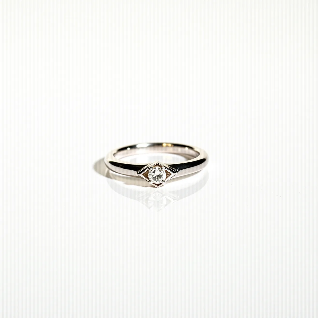 This silver wedding ring features a sleek band crafted from polished silver, enhancing its elegant appearance. At its center is a single, round-cut diamond, securely set in a simple yet sophisticated prong setting that allows the stone to capture and reflect maximum light. The ring showcases classic design elements that highlight the brilliance of the diamond while maintaining a timeless elegance, all without the need for clasps or additional attachments.