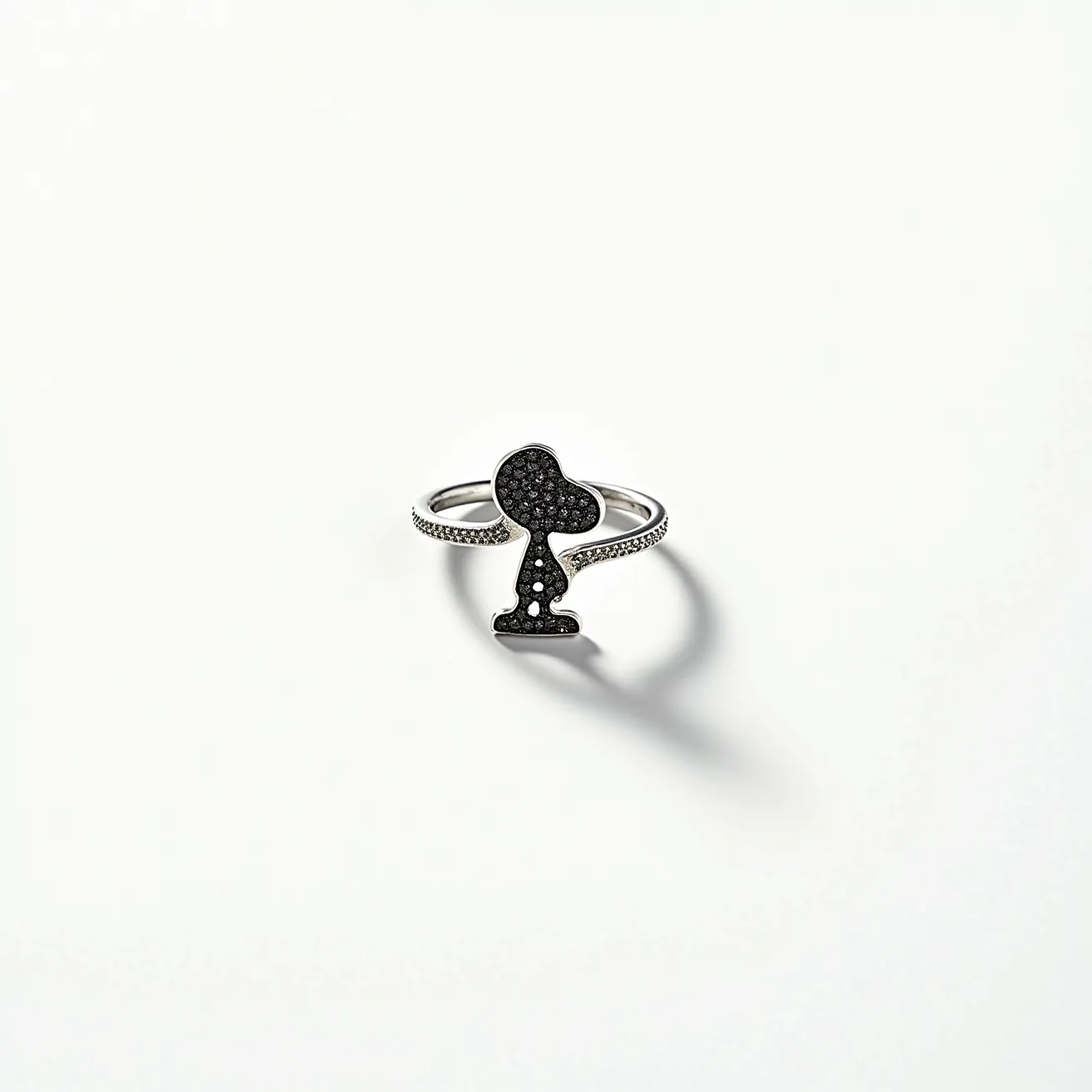 This Snoopy ring features a charming depiction of the beloved character crafted in a dark, likely oxidized metal to highlight its silhouette. The body of the design is encrusted with numerous tiny, round-cut black stones, possibly black diamonds or another dark gemstone, set in a pavé style, which creates a textured, sparkling effect across the surface. The band is adorned with small white stones, likely diamonds, adding elegance and contrast, emphasizing the character silhouette. The overall construction suggests a delicate double-band design that seamlessly integrates with the main Snoopy figure, creating a cohesive and playful yet sophisticated piece of jewelry without any visible clasps or additional attachments.