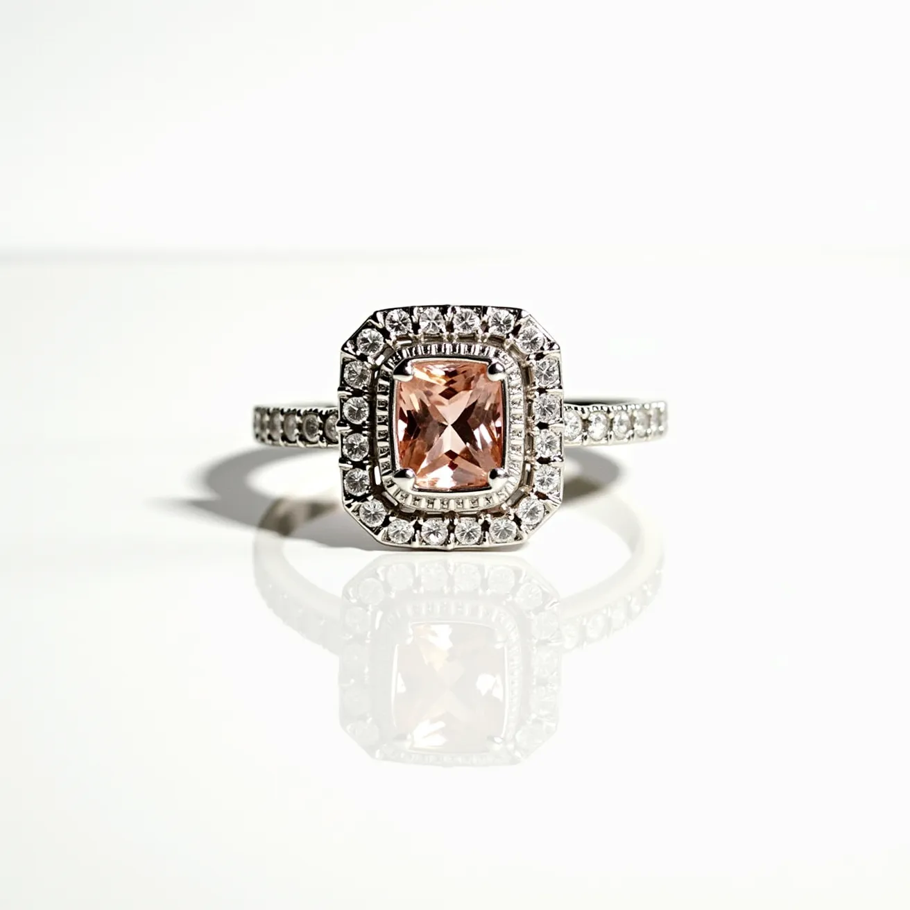 This solitaire ring features a cushion-cut stone, likely a peach or pink gemstone, set in a halo style with numerous smaller diamonds encircling the central gem. The band is crafted from a reflective metal, possibly white gold or platinum, and is adorned with additional small diamonds that extend halfway around. The setting accentuates the brilliance of the gems, with prongs securely holding the central stone while emphasizing its elegance. The overall design is sophisticated and intricate, showcasing a blend of classic and modern elements in its composition.