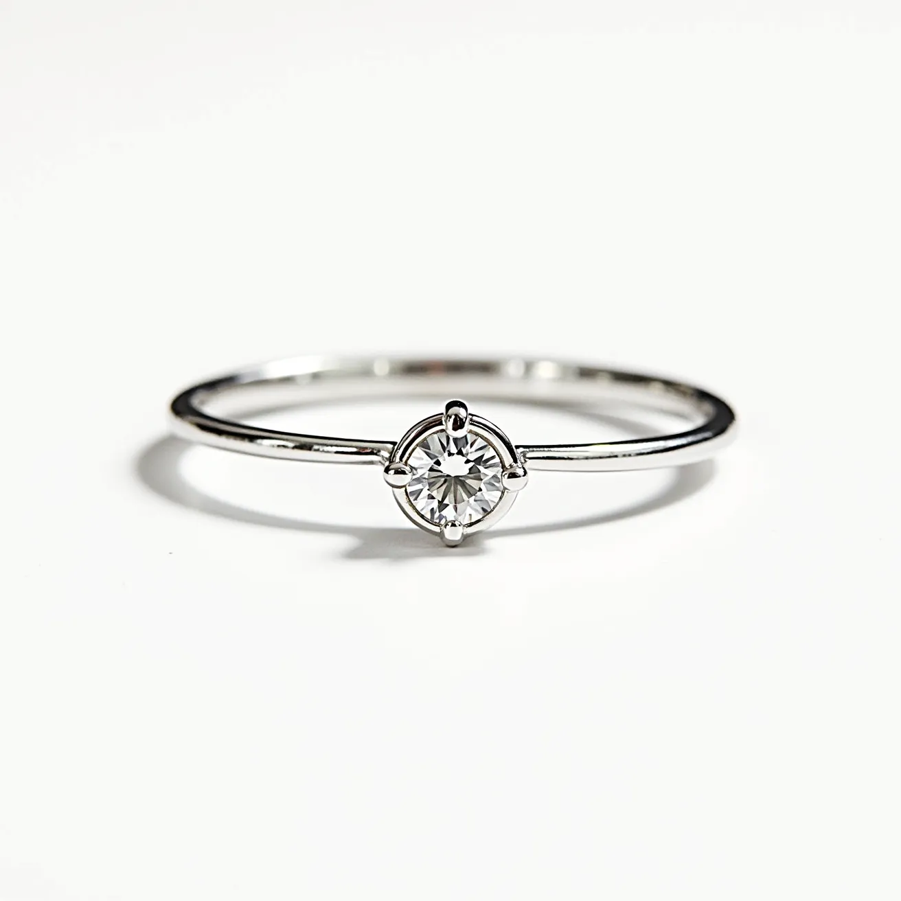 This solitaire ring features a sleek band crafted from a polished metal, likely white gold or platinum, which offers a refined and modern appearance. At its center, the ring showcases a single round brilliant-cut diamond, set in a minimalist four-prong setting that ensures a secure hold while maximizing light reflection and brilliance. The classic design emphasizes the solitaire diamond, allowing it to stand out as the focal point of the piece. The overall aesthetic is one of elegance and simplicity, making it a timeless choice for various occasions.