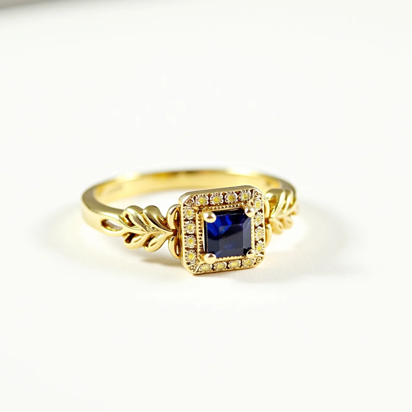 This Solomon's ring features a gold band with a detailed design reminiscent of leaves or vines on each side. At the center is a square-cut blue sapphire, securely held in a prong setting. Surrounding the sapphire is a halo of small, round diamonds, enhancing the ring's elegance. The craftsmanship of the setting accentuates the brilliance of the gems, creating a striking contrast with the gold band.