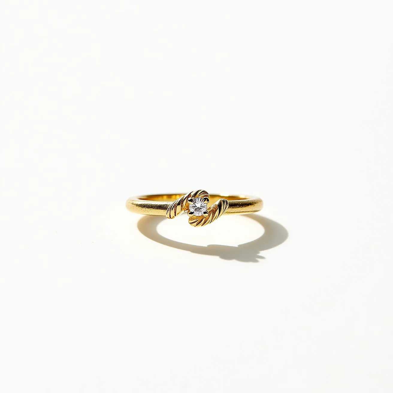 This solomons ring features a gold band with a textured finish, adding elegance to its simple design. The focal point is a single, round-cut diamond set in the center, accentuated by two gold leaf-like motifs on either side that hold the gemstone securely. The setting appears intricate, enhancing the brilliance of the diamond. The ring’s design is cohesive and classic, seamlessly blending the elements into a stable and stylish piece of jewelry.