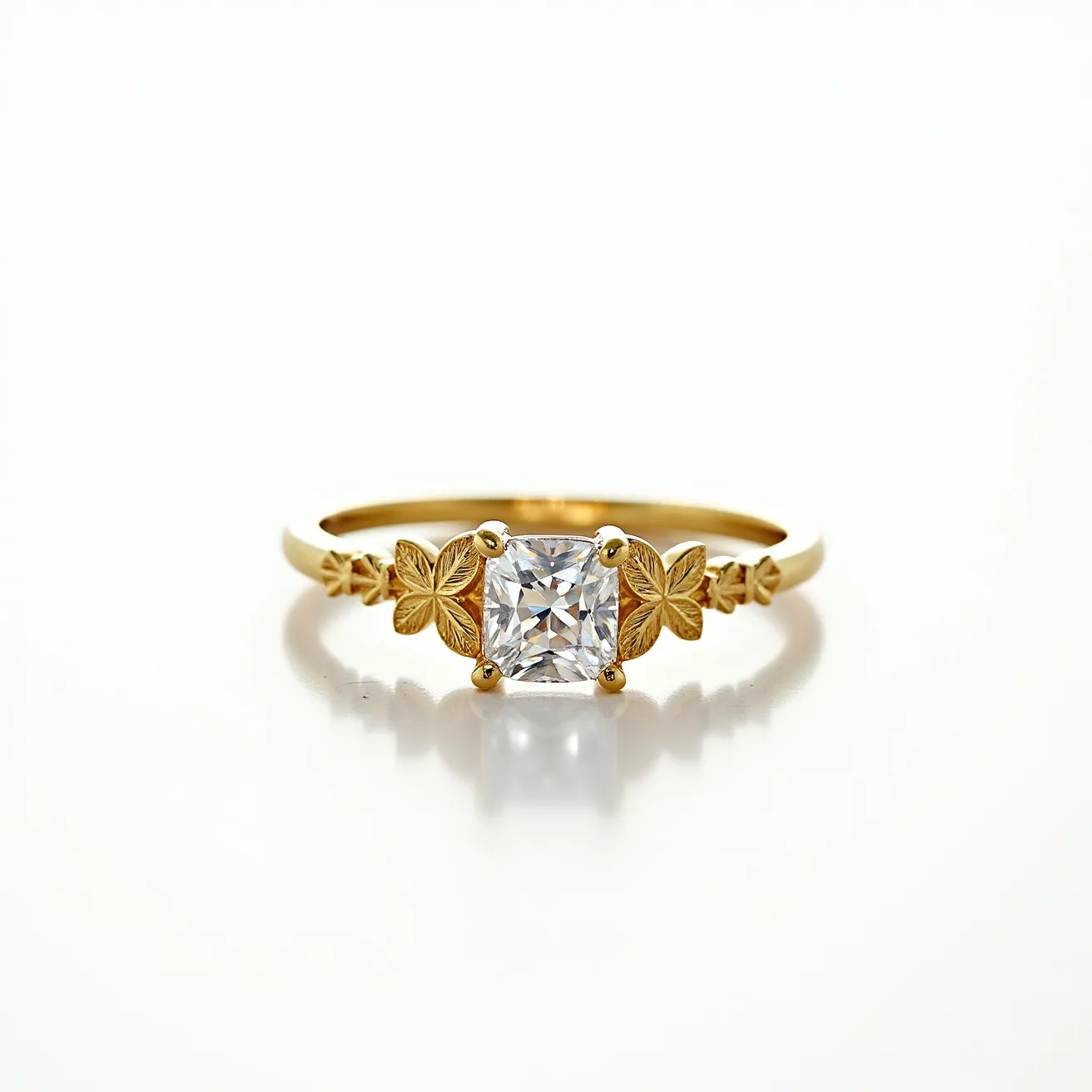 This square ring is crafted from polished gold and features a central square-cut gemstone, likely a diamond, secured in a four-prong setting. Flanking the stone are intricately designed gold floral motifs on each side, adding an elegant and decorative touch to the overall design. The band is delicately slim, complementing the ornate centerpiece while maintaining a harmonious balance between simplicity and detail. The craftsmanship highlights both the brilliance of the gemstone and the artistry of the floral accents, creating a distinctive and sophisticated piece of jewelry.