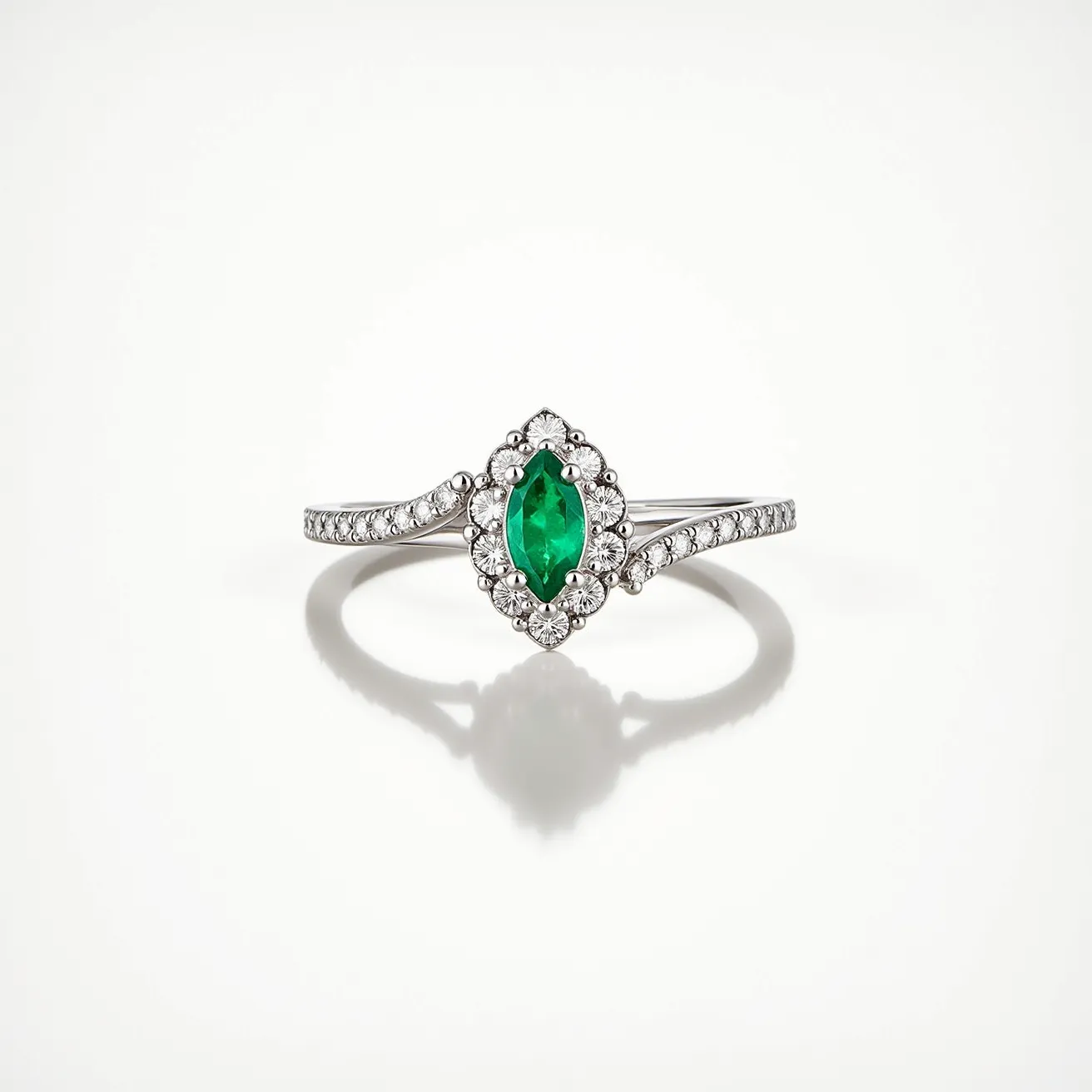 This stackable engagement ring features a striking marquise-cut emerald as its centerpiece, set in a halo of small round diamonds that accentuate its vibrant green hue. The band appears to be crafted from a polished white metal, likely white gold or platinum, which complements the sparkle of the diamonds. The diamonds are pave-set along the band, seamlessly integrating with the overall design and enhancing its elegance. The ring showcases a delicate and refined structure, allowing it to be worn alone or stacked with other rings for a personalized look.