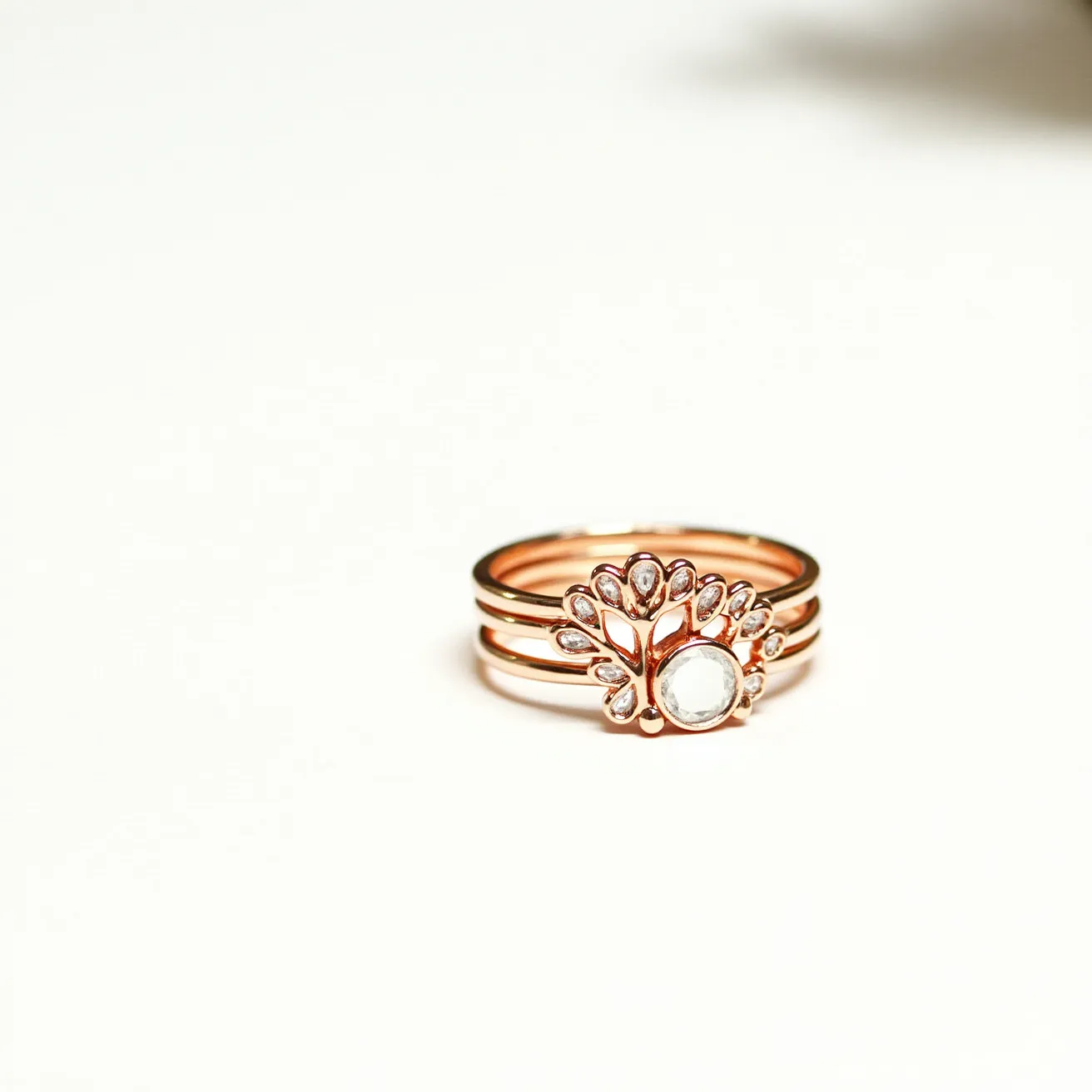 These stackable mothers rings are crafted from rose gold, featuring a central round-cut transparent gemstone, likely a moonstone, set in a bezel setting. The main gemstone is surrounded by an intricate design that resembles a floral or peacock motif, highlighting smaller marquise-shaped stones that appear to be diamonds, each set in a prong setting. The bands are smooth and polished, allowing the rings to stack seamlessly together without any visible clasp or attachment, offering both elegance and versatility for different styling options.