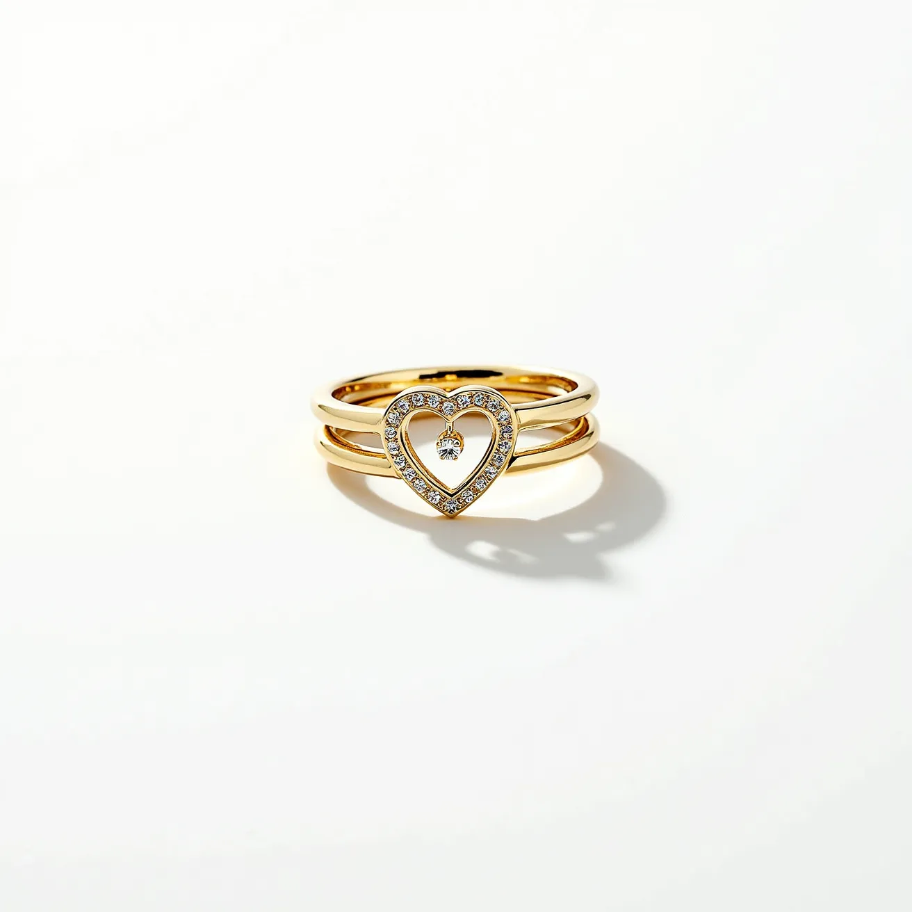 This stackable mothers ring features three elegant bands crafted from what appears to be a polished yellow gold material. The focal point is a heart-shaped design adorned with small, sparkling gemstones, likely diamonds, set in a pavé setting that elegantly outlines the heart. Within the center of the heart, a single round-cut gemstone dangles freely, adding an element of movement and charm. The absence of any visible clasps or attachments suggests that the rings are designed to be worn seamlessly together, creating a unified and elegant statement piece.