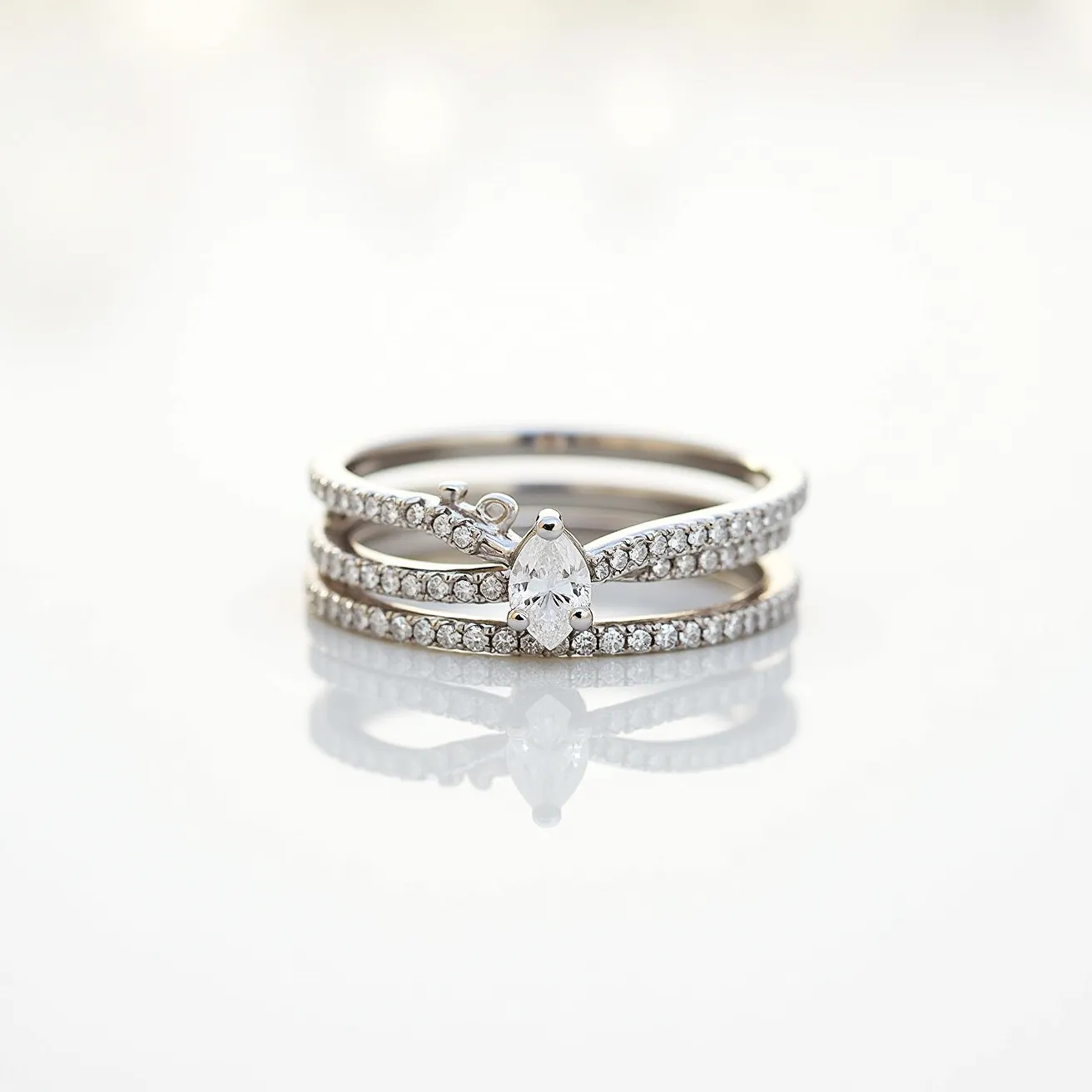 These stackable rings feature a sleek and elegant design with a combination of precious metals and gems. The primary material appears to be a polished metal, likely white gold or platinum, providing a sophisticated base. Each ring is adorned with small, round-cut diamonds, intricately set in a pave setting that enhances their brilliance and sparkle. The centerpiece of the design is a prominent pear-shaped diamond held securely in a classic prong setting, adding a focal point of interest and elegance. There is no visible clasp or attachment, allowing for seamless stacking and wear.