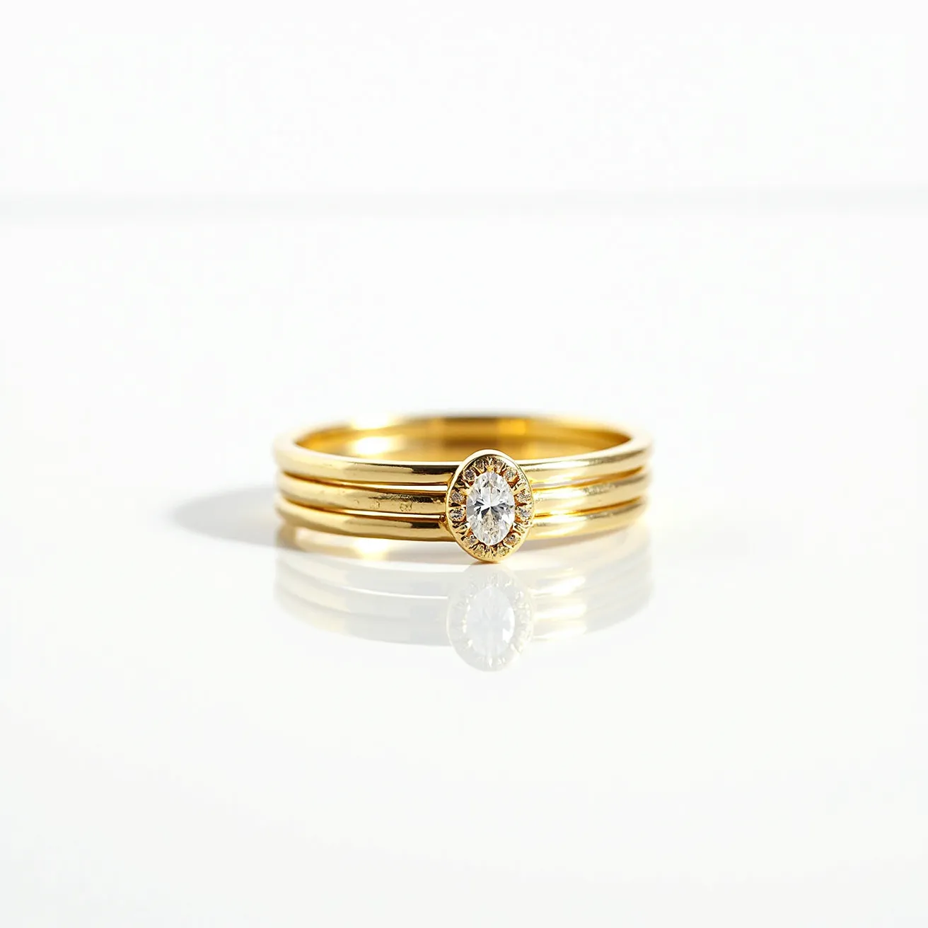 These stackable rings are crafted from polished gold and feature a central, prominently set oval-cut gemstone, likely a diamond, in a bezel setting. The gemstone is encircled by a delicate halo that enhances its brilliance and elegance. The rings are designed to be worn together, each maintaining a sleek and minimalist profile that accentuates the central stone. There are no visible clasps or attachments, as the rings rely on their form-fitting design for secure wear.