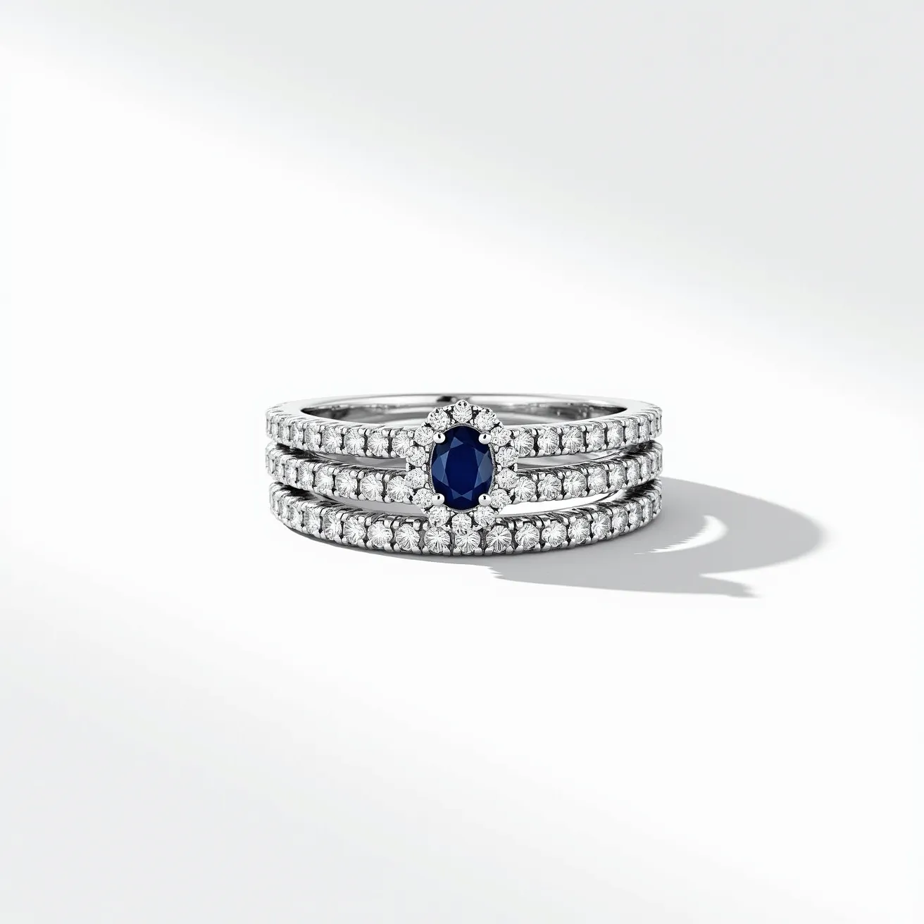 These stacked wedding rings feature a central ring adorned with a prominent oval-cut sapphire set in a halo setting, surrounded by a circle of round diamonds that enhance its elegance. The two additional bands are each lined with round-cut diamonds, beautifully complementing the central sapphire ring. All three rings are crafted from a lustrous metal, likely white gold or platinum, which provides a sleek and refined backdrop for the dazzling stones. The uniformity and symmetry of the setting highlight the brilliance of the diamonds, creating a harmonious and sophisticated ensemble.