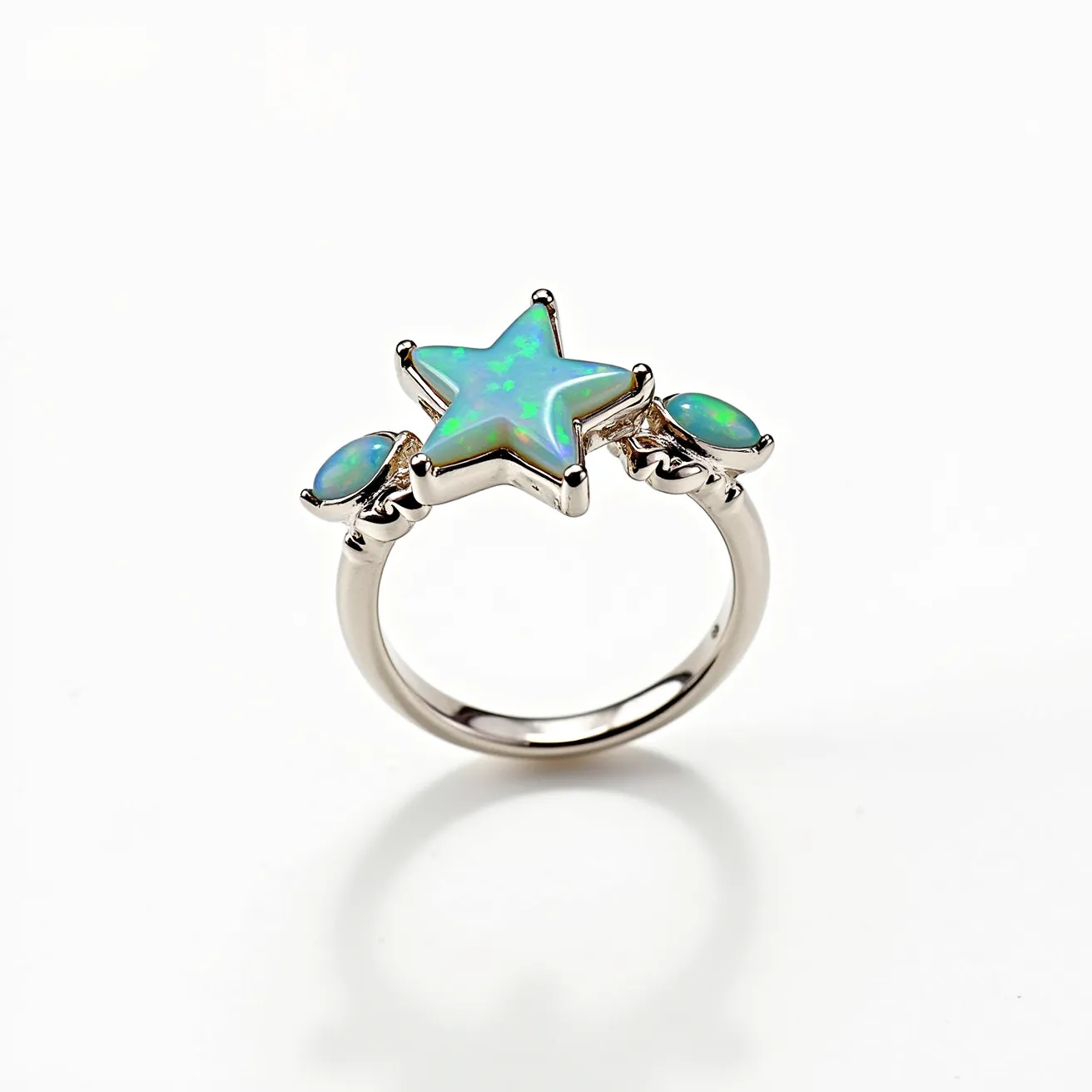 This star ring features a captivating design with a central star-shaped opal stone, exhibiting a vibrant play of green and blue colors. Flanking the star are two smaller oval opals, similarly displaying a brilliant iridescence. The stones are set in a sleek, metallic band, likely crafted from sterling silver or white gold, offering a luminous backdrop that enhances the opals' vivid hues. The opals appear to be bezel-set, providing a secure and smooth finish without any visible clasps or attachments, emphasizing a seamless and elegant aesthetic.