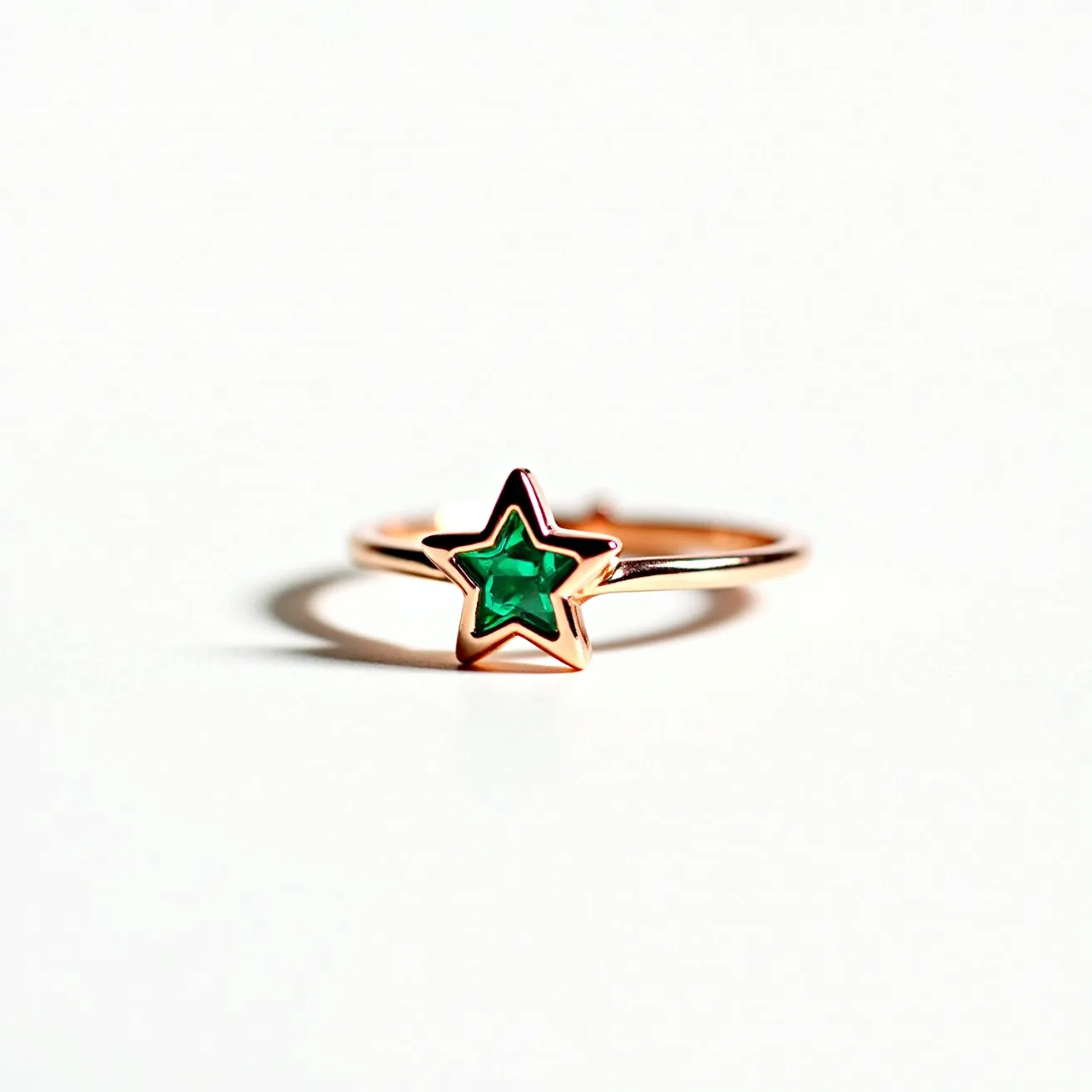 This star ring features a delicate band crafted from a gold-toned metal, offering a warm and elegant appearance. At the center, a star-shaped green gemstone is prominently set, possibly an emerald, cut to fit snugly within the star outline of the setting. The gemstone is smoothly positioned in a bezel setting, providing both security and a contemporary aesthetic. The design is sleek and minimalist, highlighting the brilliance and cut of the star-shaped stone without additional clasps or attachments.