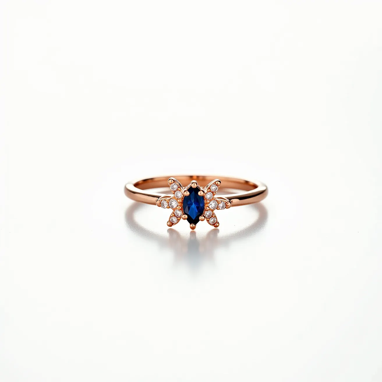 This star ring features a delicate band crafted from rose gold, accentuating its warmth and elegance. At the center, it showcases a marquise-cut blue sapphire, adding depth and a pop of vibrant color. Surrounding the sapphire, small brilliant-cut diamonds are set in a star pattern, enhancing the ring's celestial theme. The diamonds are securely held with prongs, ensuring their stability and sparkle. The overall design highlights a beautiful blend of color and brilliance, with precise craftsmanship evident in the setting of each gem.