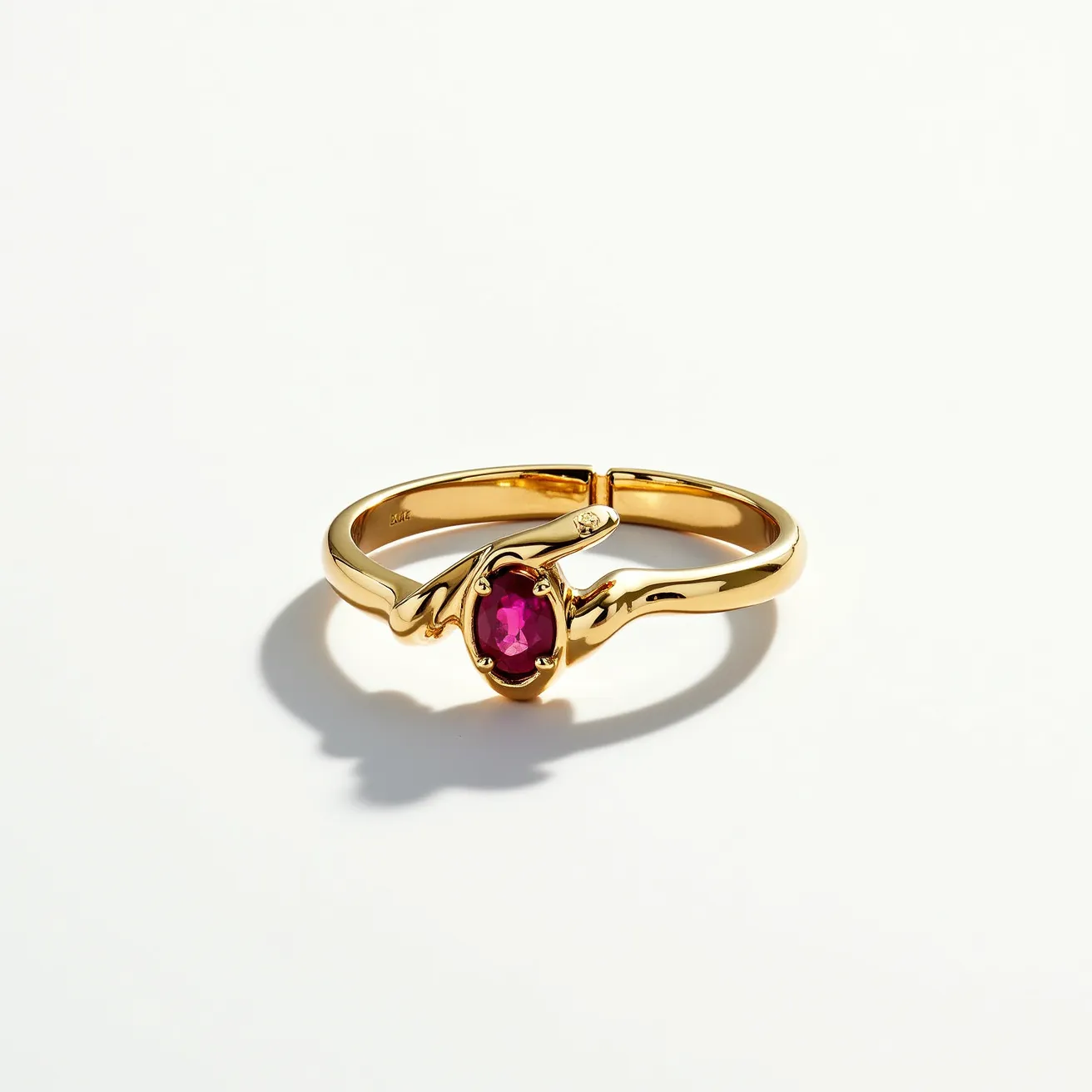 This statement ring features an elegant gold band that gracefully wraps around the finger. At its center is an oval-cut, deep red gem, likely a ruby, which is held securely in a bezel and prong setting, providing both style and durability. The gold band has a smooth, polished finish that enhances the overall opulence of the piece, and the design includes a distinctive crisscross arrangement around the gemstone, adding a modern twist to its classic allure.