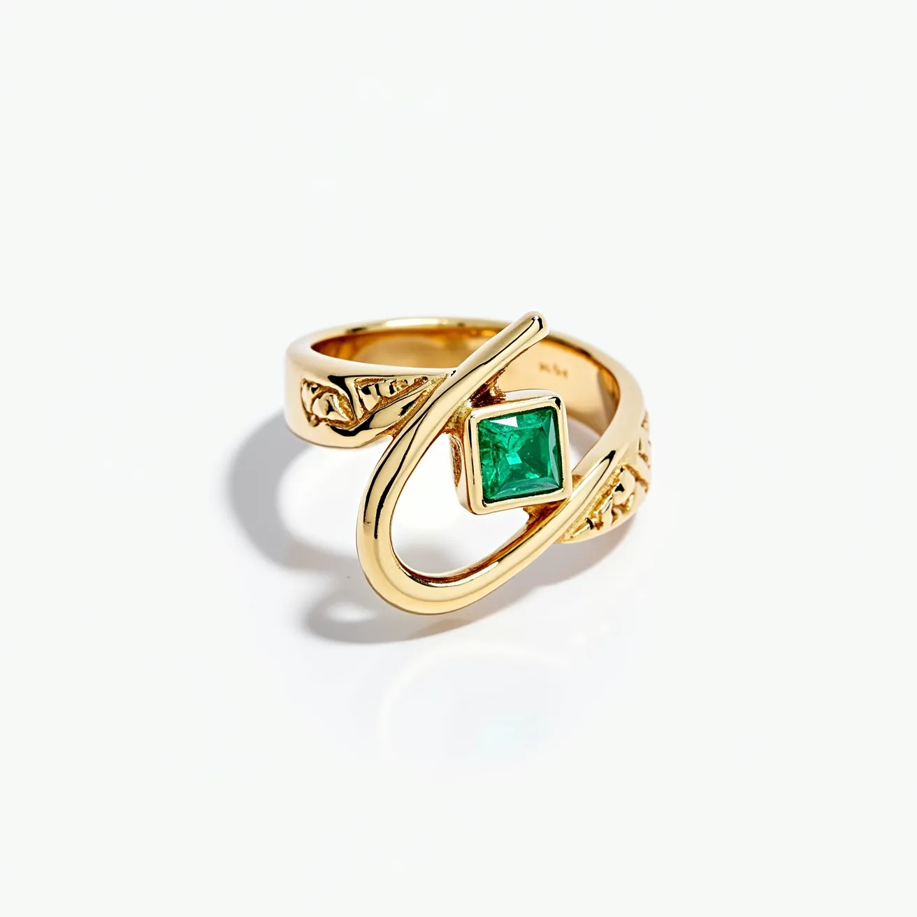 This statement ring features a bold, artistic design crafted from lustrous gold metal. At the center, a striking square-cut emerald is securely set in a bezel setting, drawing attention with its rich green hue. The band of the ring displays intricate detailing, adding an elegant touch to its overall appearance. The unique open loop design of the band wraps around the gem, enhancing its contemporary and sophisticated style. The ring’s captivating elements make it an eye-catching piece suitable for making a fashionable statement.