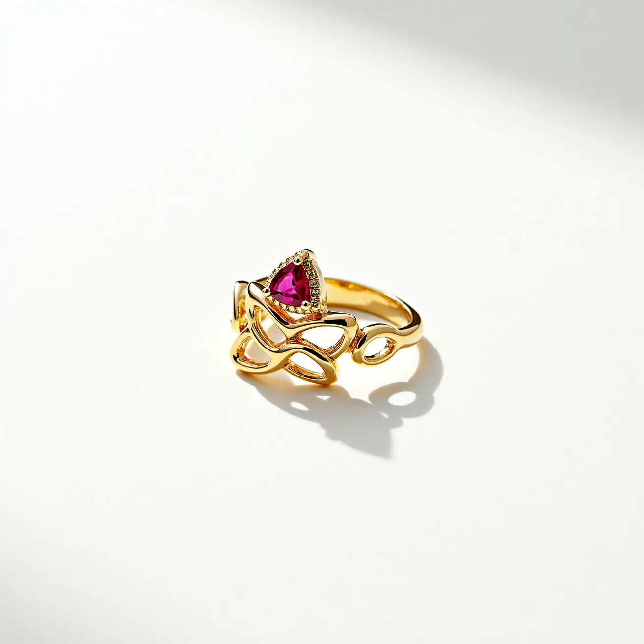 This statement ring features an elegant design crafted from gold-toned metal, characterized by its intricate looping pattern. At the center, there is a striking, triangular-cut pink stone set in a bezel setting, adding a vibrant pop of color. The openwork design enhances its decorative appeal, with a polished finish that catches the light beautifully. The ring does not include additional clasps or attachments, allowing the arrangement and the gemstone to stand out as the focal point.