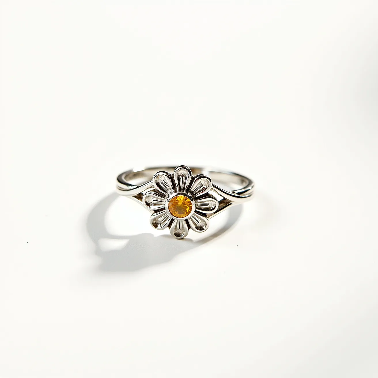 This sunflower ring features a delicate design with a metallic band likely crafted from silver or a similar material. At the center of the floral motif is a round-cut, yellow gemstone set in a bezel-style setting, resembling the vibrant core of a sunflower. The petals radiate outward from the center stone, emphasizing the floral theme. The ring does not appear to have any additional clasps or attachments, suggesting a simple slip-on style that elegantly adorns the finger.