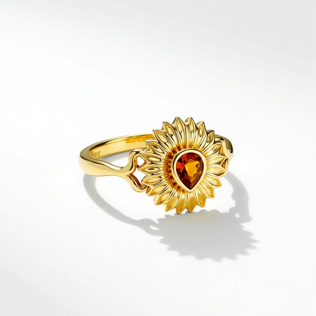 This sunflower ring features a detailed floral design crafted from gold-tone metal, forming the shape of a sunflower. At the center is a teardrop-shaped gemstone with a warm, amber hue, likely a citrine, held in place by a bezel setting that mirrors the flower's shape. The band is sleek and smooth, seamlessly merging with the sunflower design, showcasing a delicate and elegant aesthetic. The craftsmanship and choice of materials create a vibrant and nature-inspired piece of jewelry.