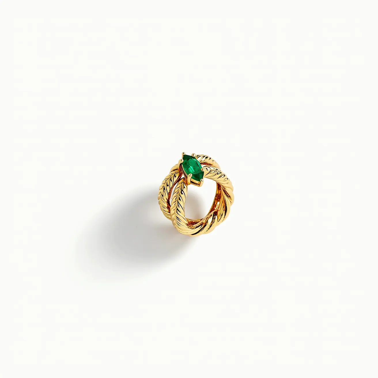 This tangled ring features interwoven bands of gold that create a textured, rope-like appearance, adding a sense of complexity and elegance. At the center, a marquise-cut green gemstone is prominently displayed, secured by prongs in a prong setting, enhancing its visibility and brilliance. The intricate design and choice of materials suggest a piece that is both luxurious and thoughtfully crafted.