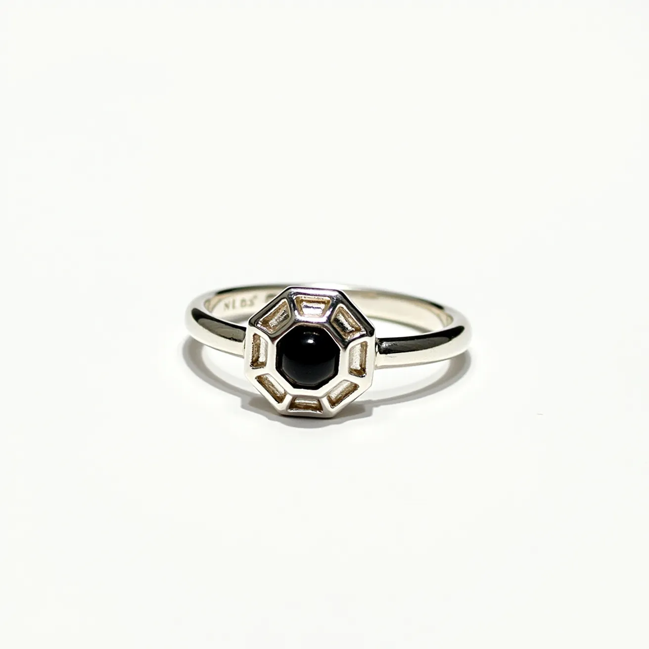 This thumb ring features a sleek, metallic band likely made of silver, giving it a polished finish. At its center is a black stone, which appears to be round-cut, set within an octagonal bezel setting that accentuates its shape. The geometric design of the setting adds a modern and bold touch to the piece, contrasting elegantly with the simplicity of the band. The ring does not incorporate any additional clasps or attachments, maintaining a streamlined and cohesive design.