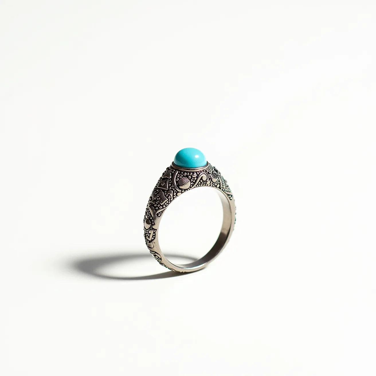 This thumb ring features an intricately detailed metal band with ornate patterns that add texture and elegance. At its center, it showcases a polished turquoise cabochon, distinguished by its smooth, rounded surface. The turquoise stone is securely set in a bezel setting, which complements the overall antique-inspired design of the ring. The choice of silver or silver-toned metal for both the band and the setting enhances the vibrant blue of the turquoise. The ring does not include any additional clasps or attachments, maintaining a classic circular form.