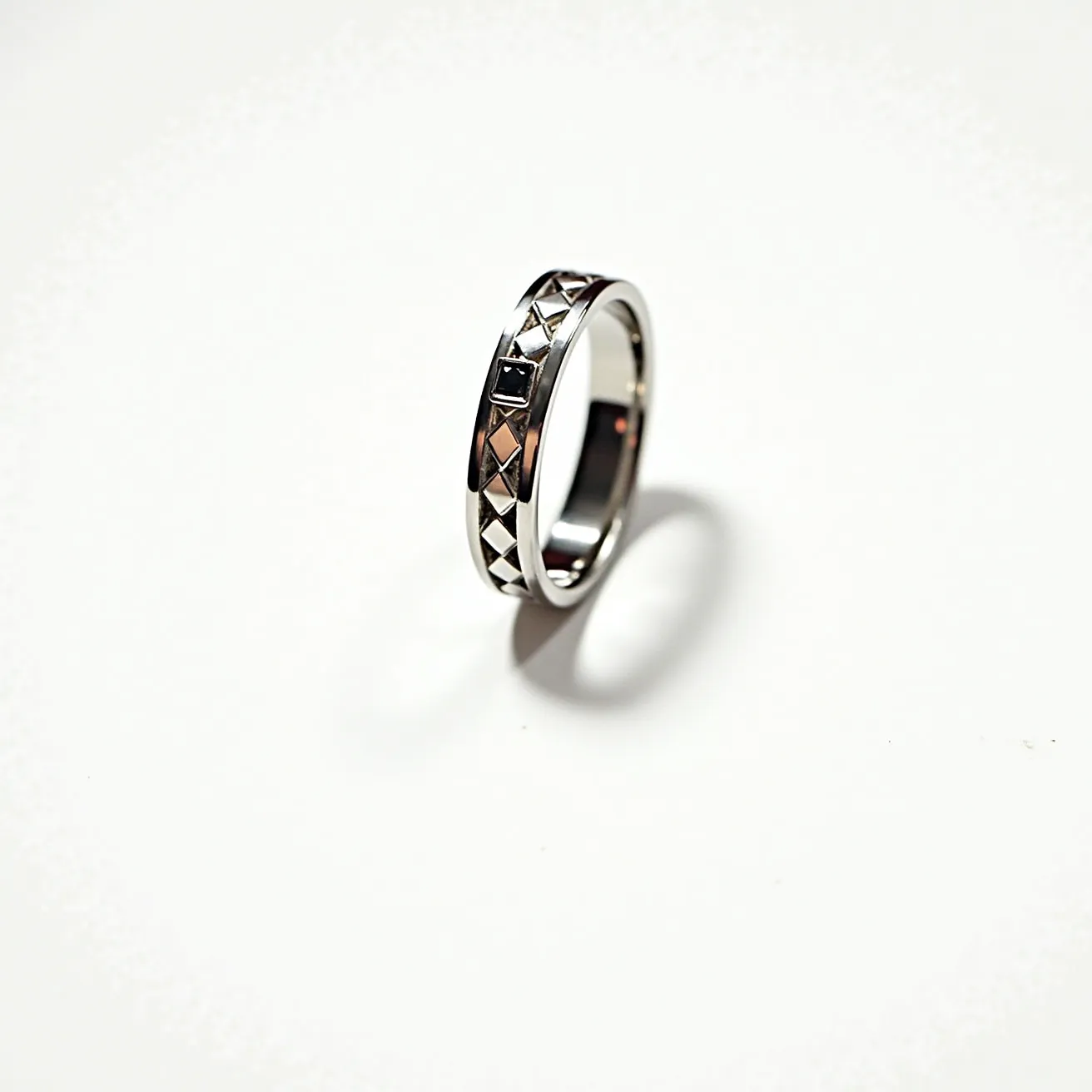 This tungsten ring features a sleek and polished silver-grey band with a distinctive geometric design. The band showcases a repeated pattern of diamond-shaped engravings, providing texture and visual interest. Within the pattern, a single black square gem is set, adding a striking contrast to the metallic sheen of the tungsten. The gem appears to be flush with the band in a channel setting, ensuring a smooth profile and comfortable wear. There are no clasps or attachments, allowing the ring to slip effortlessly onto the finger.