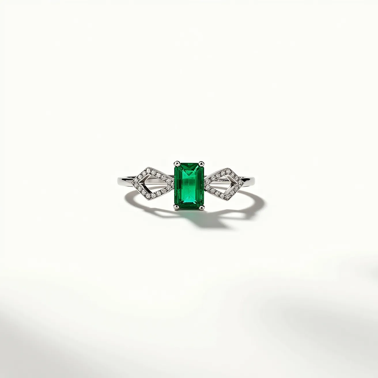 This two birthstone ring features a central emerald-cut green gemstone set in a sleek metal band, likely composed of polished white gold or platinum. The center stone is securely held by four prongs, enhancing its bold presence. Flanking the central gem are two diamond-shaped settings, each encrusted with small round white diamonds, adding a touch of elegance and sparkle. The ring’s design seamlessly integrates the gems and the metal, creating a balanced and sophisticated piece.