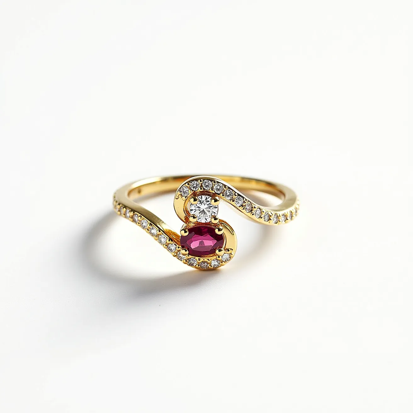 This two birthstone ring features an elegant loop design crafted from a lustrous yellow metal, likely gold, which forms the band and primary structure. The ring showcases two prominent gemstones: a round, brilliant-cut diamond that sparkles with clarity, and an oval-cut ruby that exudes a deep, rich red hue. These stones are set in a delicate, intertwining fashion with the diamond positioned above the ruby in an ornate, curvilinear setting. The band is encrusted with smaller, round-cut diamonds that add to the overall brilliance and sophistication of the piece.