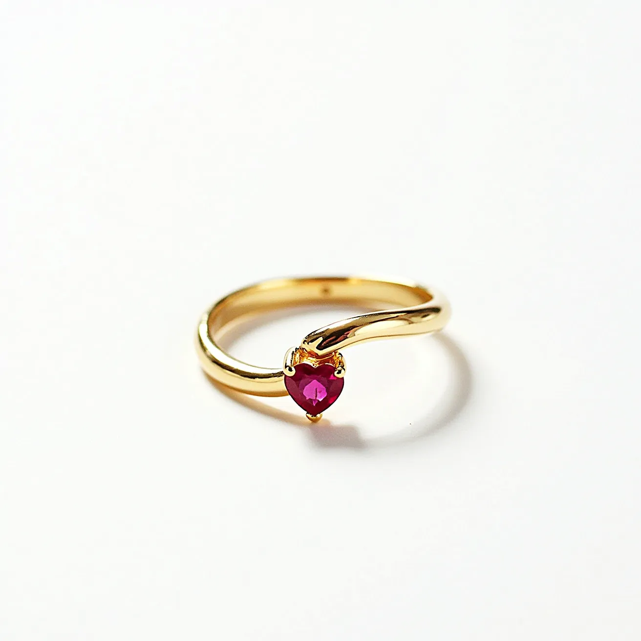 This two birthstone ring features a polished gold band that gracefully curves to securely hold a heart-shaped ruby in a prong setting. The vibrant red gemstone is expertly cut, enhancing its brilliance and charm. The ring's design places the gemstone prominently, allowing it to be the focal point. There are no visible clasps or attachments, as the ring is a single continuous band that elegantly encompasses the finger.