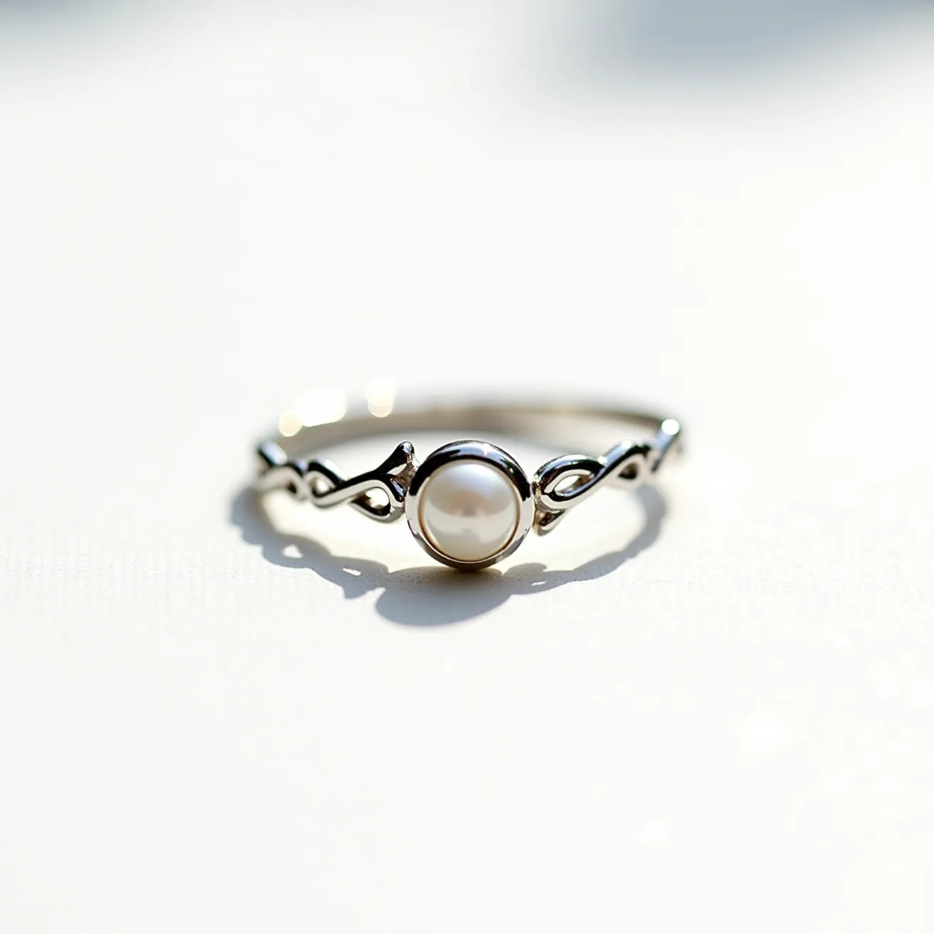 This vine engagement ring features a beautifully intricate design, crafted from a silver-toned metal that gives it a delicate and elegant appearance. Central to the ring is a lustrous pearl, smoothly spherical, set in a bezel style which securely surrounds the gemstone with a thin rim. The band itself is adorned with a vine-like motif, characterized by graceful, fluid twists and loops that accentuate its organic inspiration, contributing to the overall aesthetic of natural elegance. This combination of elements makes the ring a unique and graceful piece of jewelry.