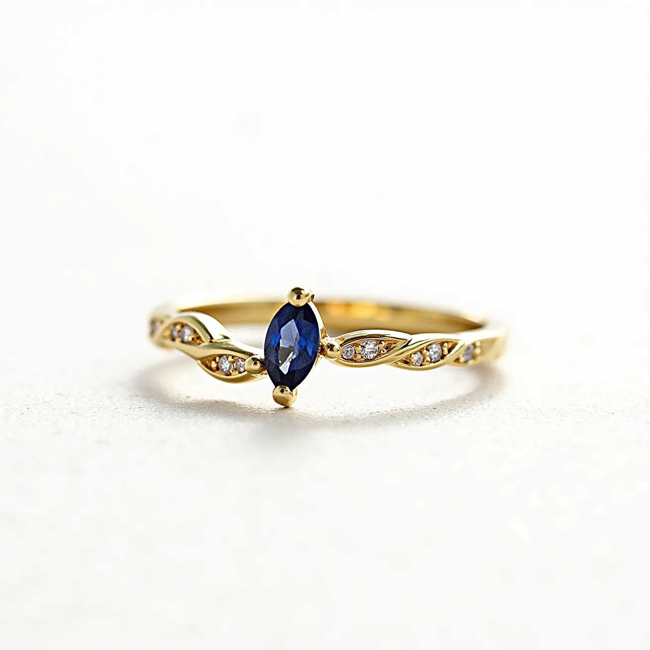 This vine engagement ring features a beautifully intricate band made of gold that resembles intertwining vines. At its center is a marquise-cut deep blue sapphire, held securely in place by a prong setting that enhances its elegance. Along the vine-like band, small round diamonds are embedded, providing delicate sparkle and additional visual interest. The design seamlessly integrates these elements to create a cohesive and enchanting piece of jewelry.