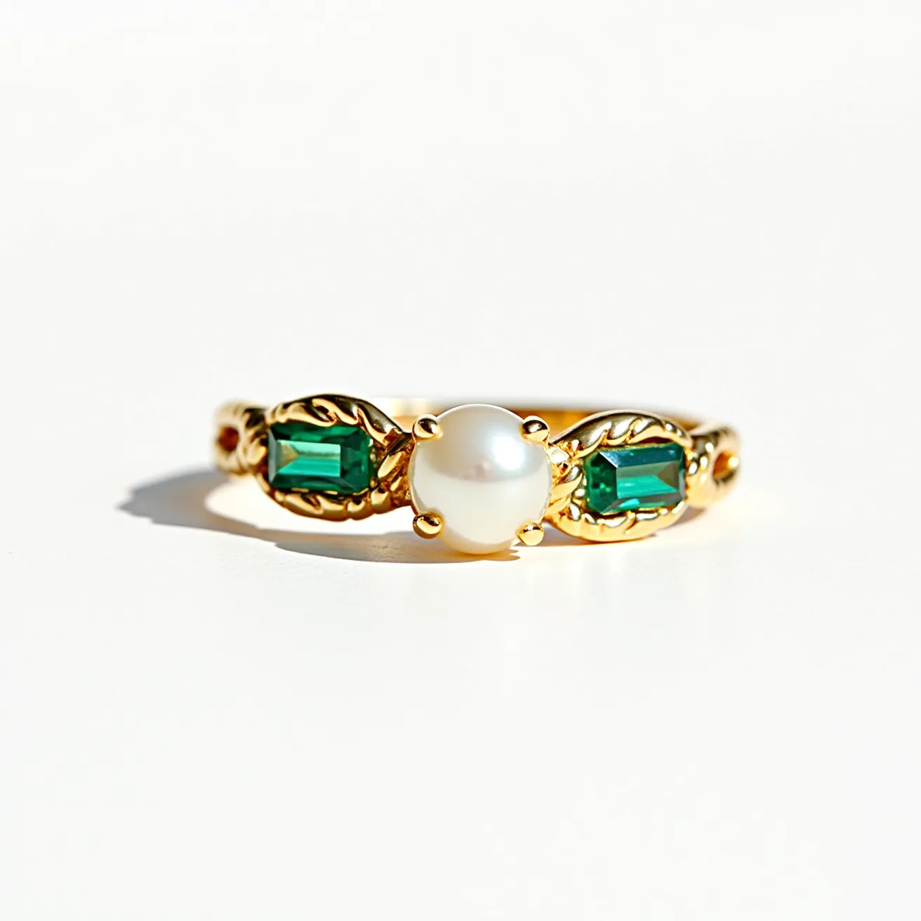 This vine ring features a central white pearl held by a delicate prong setting, flanked by two rectangular green gemstones with a baguette cut, securely set in a gold vine-like design that enhances the natural motif. The band, crafted from gold, elegantly intertwines with leaf patterns that complement the gemstones and pearl. The combination of the rich green stones and the lustrous pearl offers a harmonious contrast, while the gold metalwork adds warmth and luxury to the overall design.