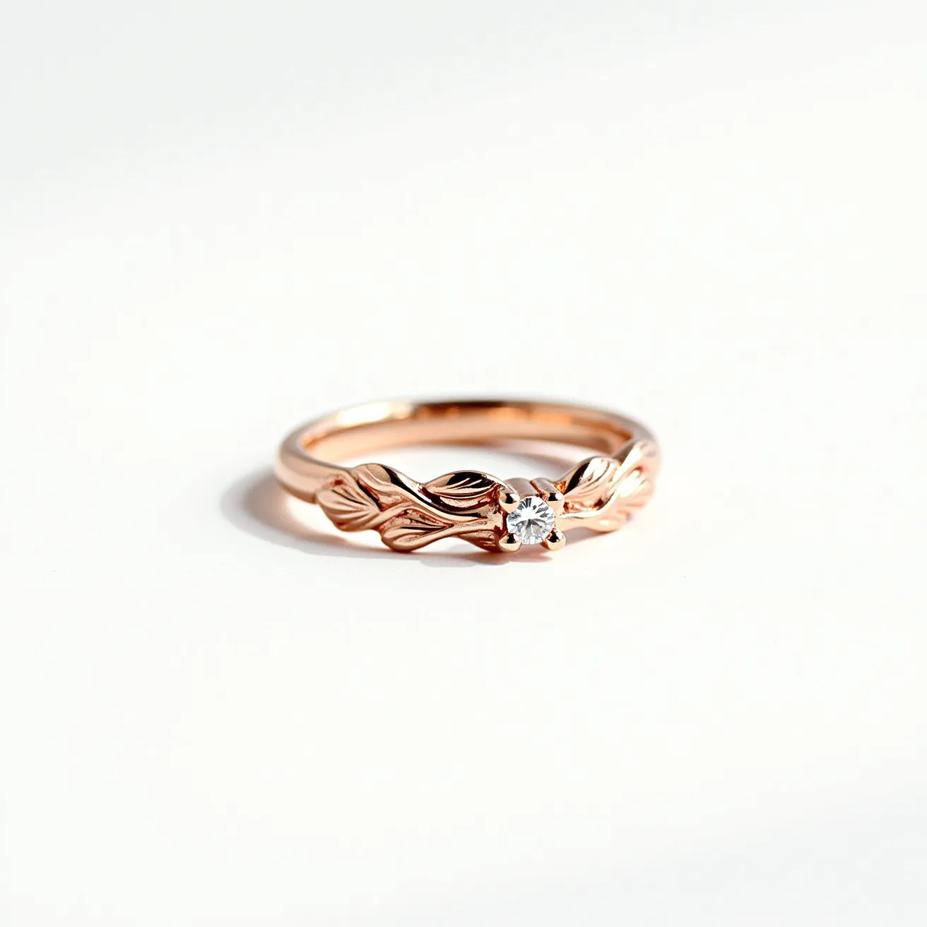 This wedding band features a delicate design crafted from rose gold, showcasing intricate leaf motifs around the band. At the heart of the ring sits a round-cut diamond, held securely in place by a classic prong setting. The blend of the organic leaf patterns with the brilliance of the diamond creates an elegant and timeless piece, emphasizing its natural inspiration and refined artistry.