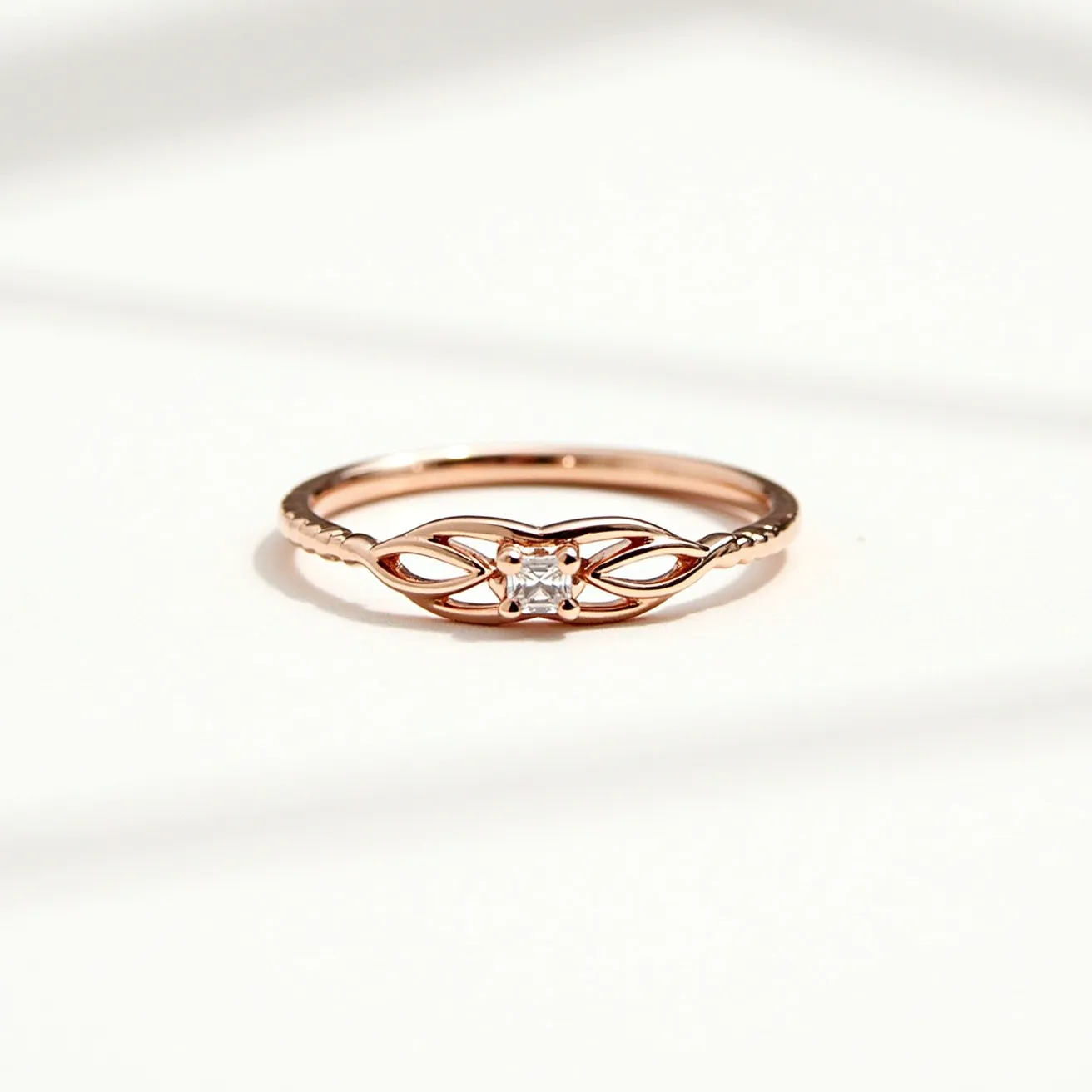 This wedding ring features a delicate rose gold band showcasing a refined openwork design that elegantly frames the central gemstone. The stone is a small, round-cut diamond set in a bezel setting, providing a secure and smooth surface. The intricate metalwork on the band enhances the overall elegance of the piece, making it a unique and refined choice for jewelry. The design integrates the gemstone seamlessly with the band, exhibiting meticulous craftsmanship and aesthetic harmony.