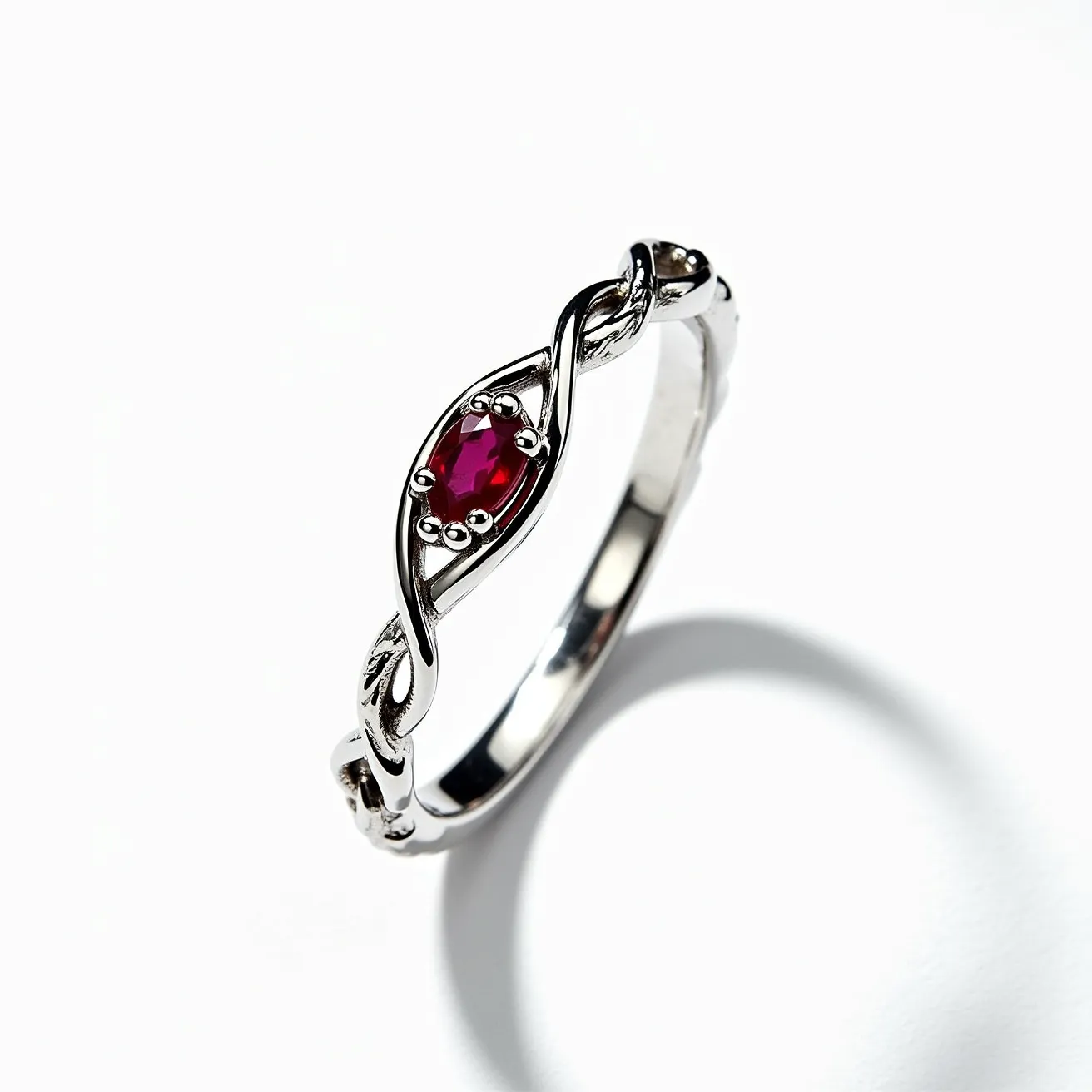 This wedding ring features a sleek metal band, likely made of white gold or platinum, that showcases an intertwined design. At its center, an oval-cut red gemstone, possibly a ruby, is securely held in a prong setting, adding a vibrant and elegant touch. The ring's design incorporates delicate twists around the stone, enhancing its overall aesthetic with a sense of fluidity and grace. There are no visible clasps or attachments present, emphasizing the ring's simple yet sophisticated style.