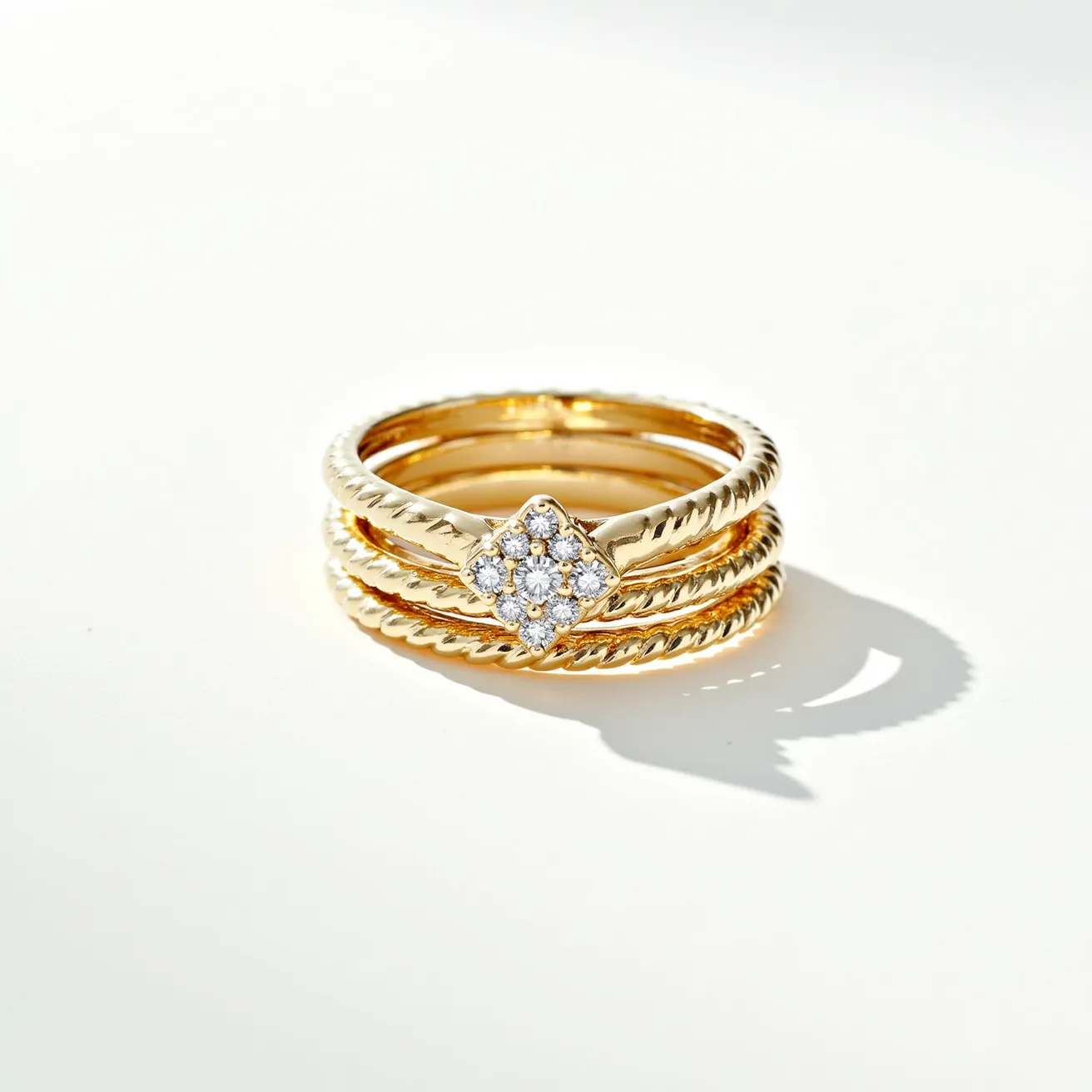 These wedding ring sets feature a trio of gold bands with a twisted design, giving a textured and elegant appearance. The central ring stands out with a cluster of small round-cut diamonds arranged in a square setting, creating a focal point of sparkle and sophistication. The diamonds are securely prong set, complementing the rich hue of the gold bands and enhancing their luxurious appeal. The rings appear to form a cohesive set, designed to be worn together or individually for versatility in style.