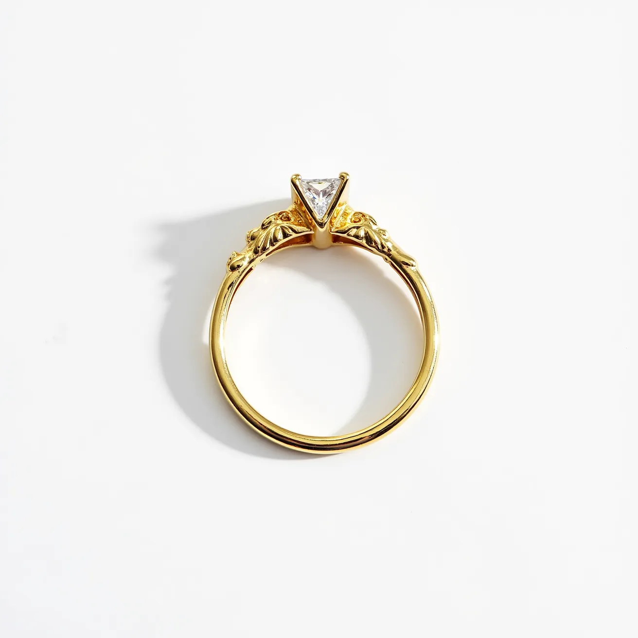 This unique wedding ring features a vibrant yellow gold band, intricately designed with ornate detailing near the setting. The centerpiece of the ring is a triangular-cut diamond, securely held in place by a prong setting that accentuates its shape and brilliance. The exquisite craftsmanship of the band enhances the overall elegance of the piece, making it a standout symbol of commitment.